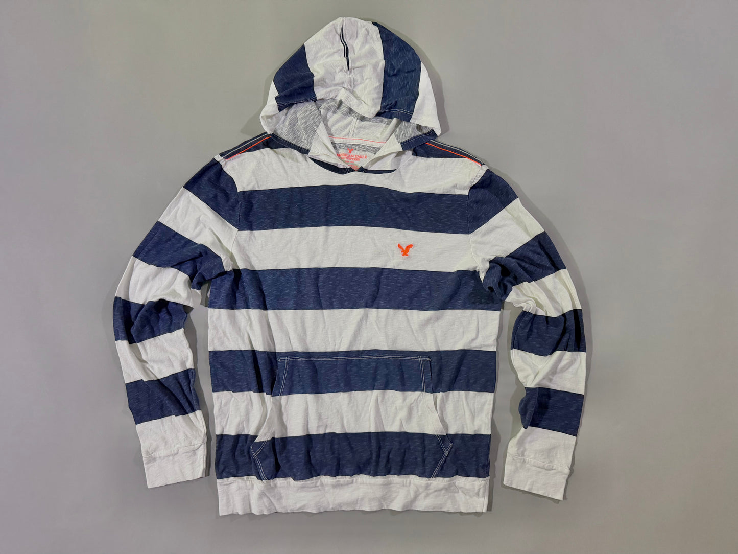Photo of a long sleeve hooded shirt from American Eagle with thick navy and white stripes and orange eagle embroidery. 
