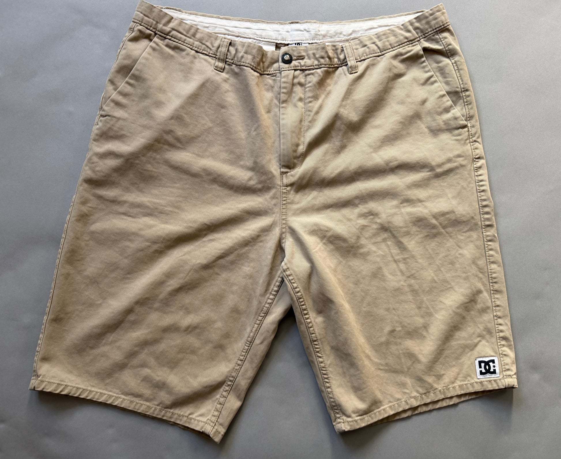 Men’s khaki DC chino skate shorts with small logo patch on bottom right hem 