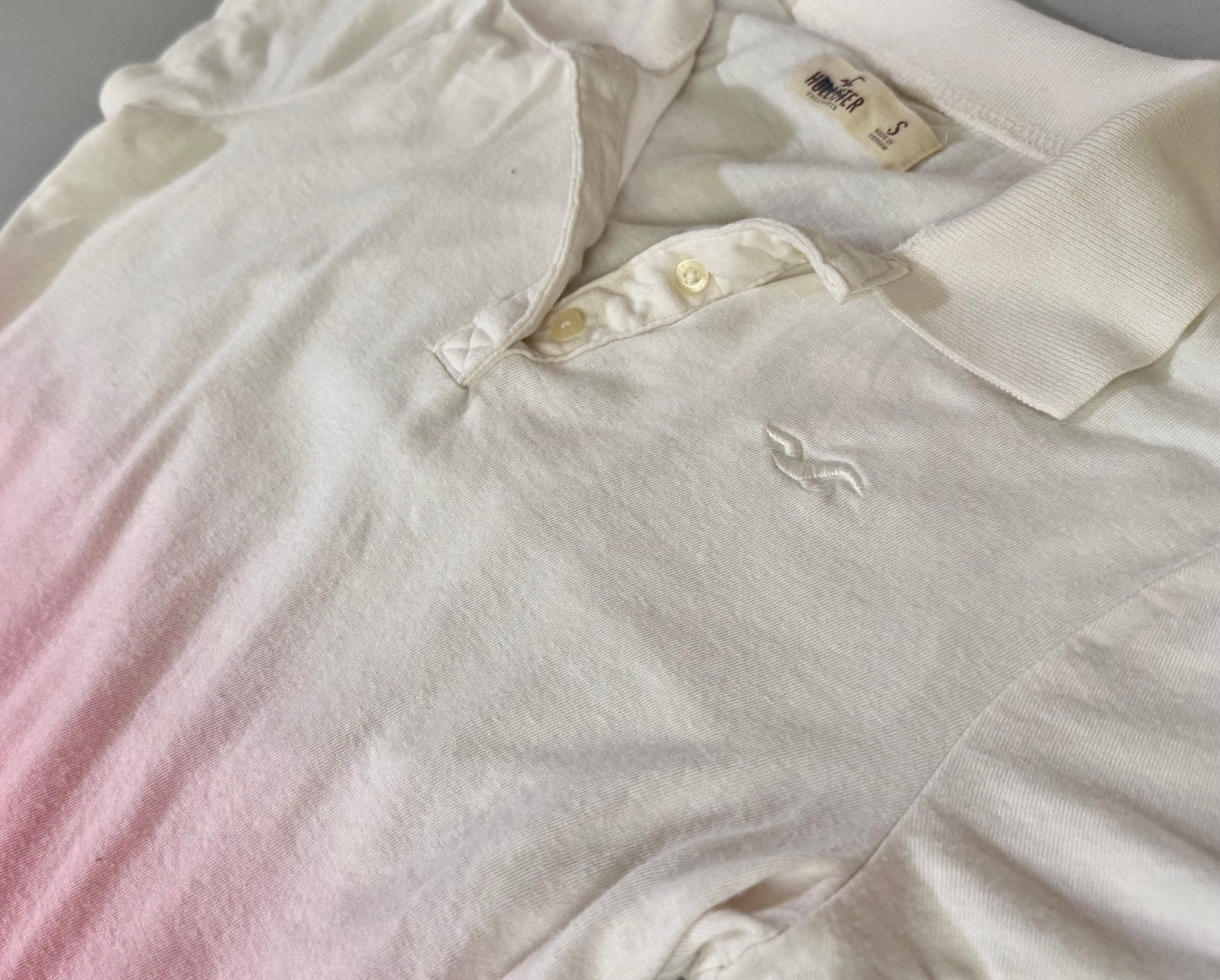 Close-up of Hollister ombré polo shirt showing collar, button placket, and embroidered seagull logo.