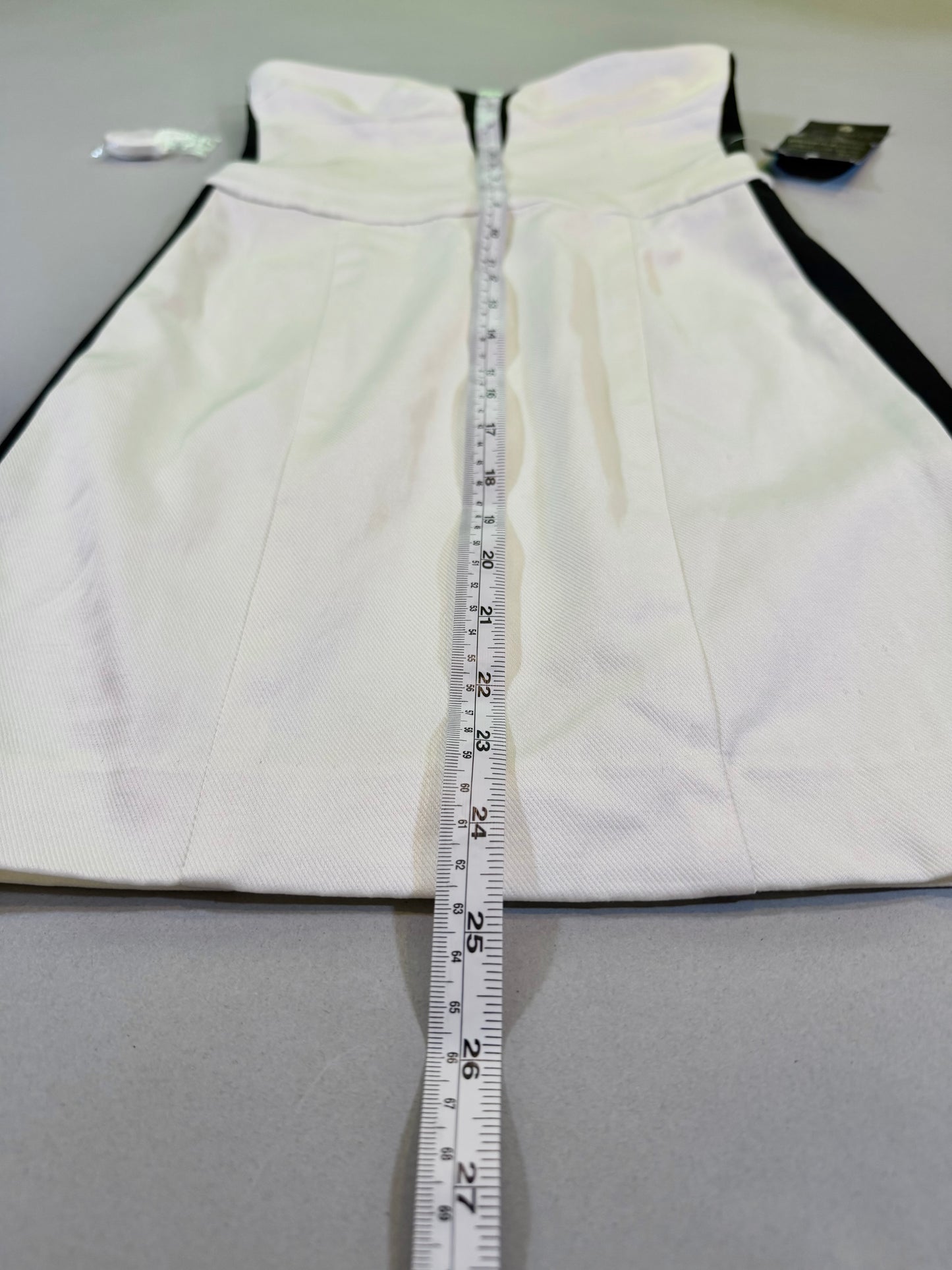 Close up of black and white mini dress and measuring tape showing 25 inches length 