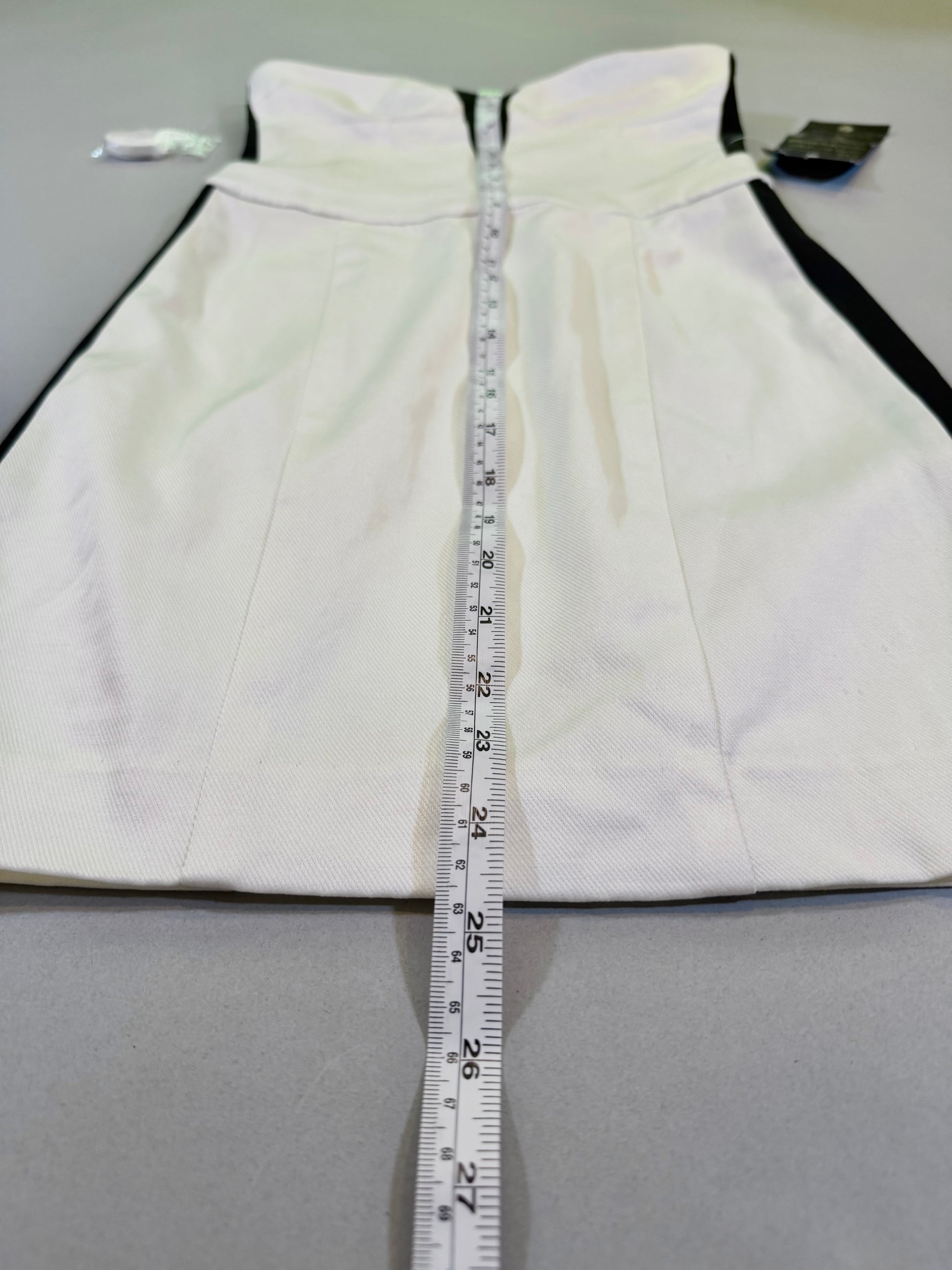 Close up of black and white mini dress and measuring tape showing 25 inches length 