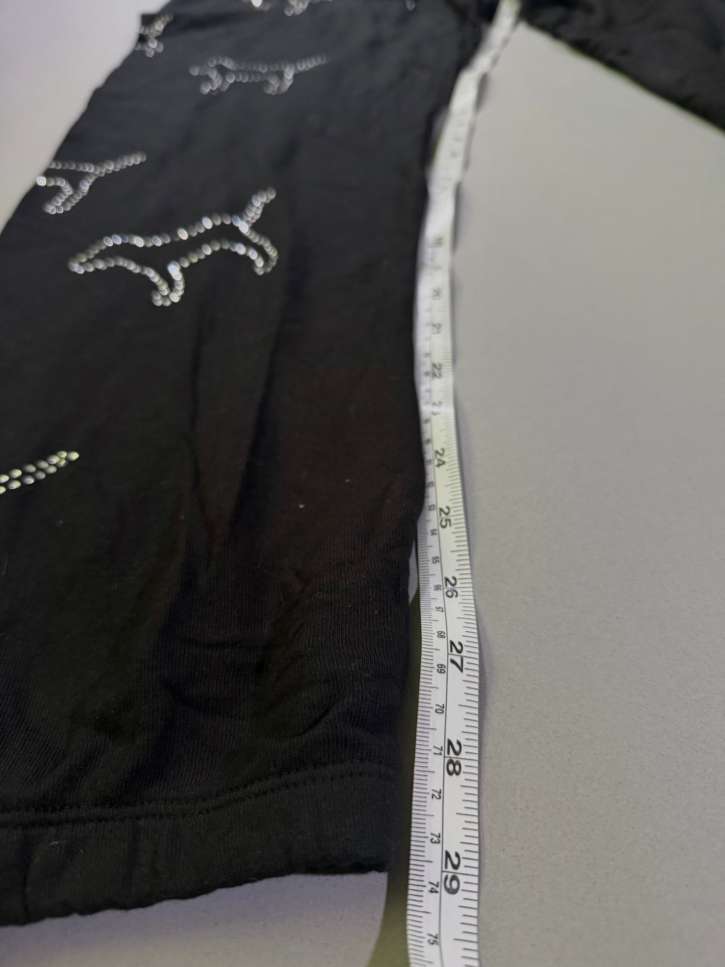 Black Victoria’s Secret jogger sweatpants with rhinestones and measuring tape showing inseam 