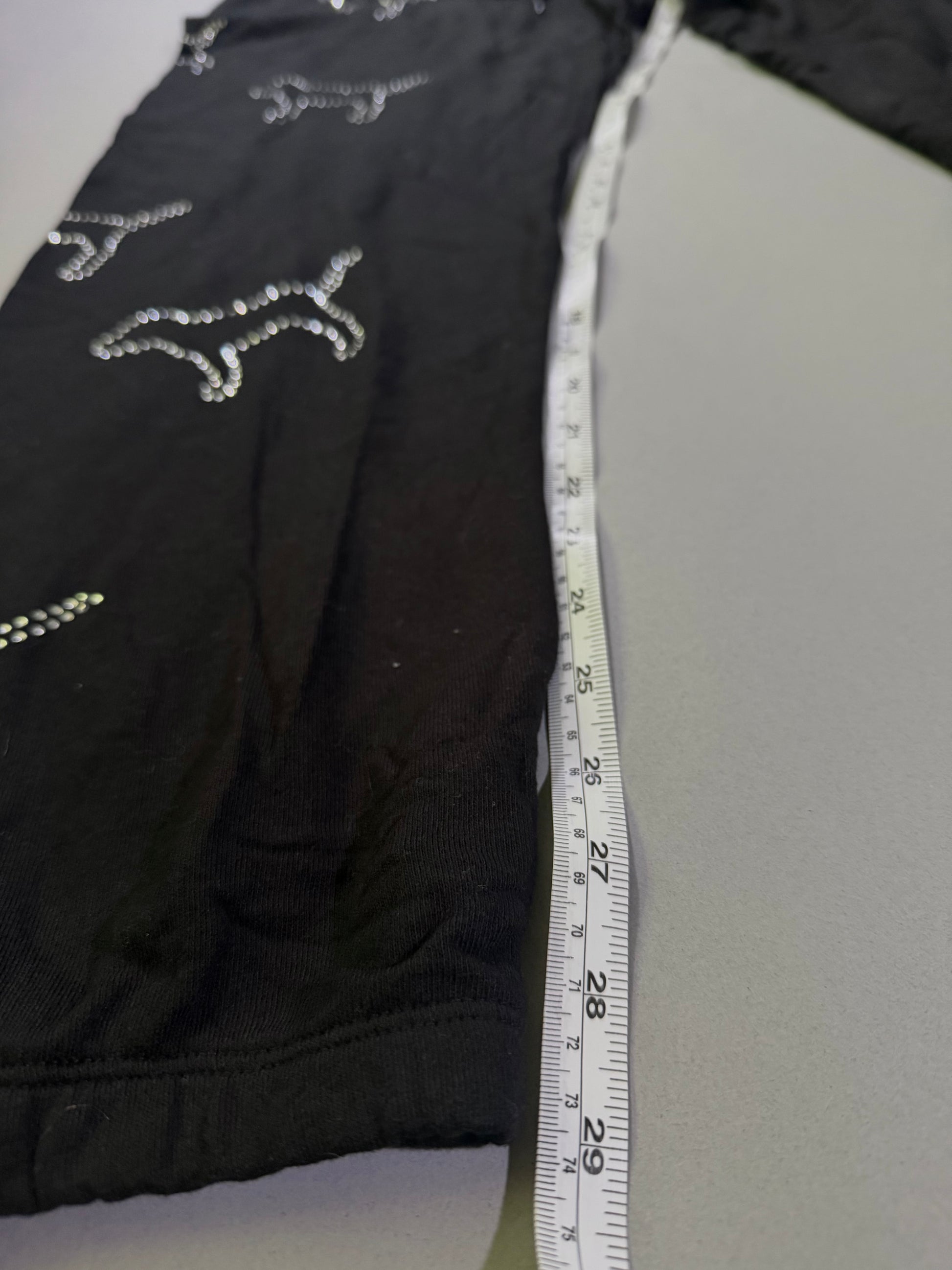 Black Victoria’s Secret jogger sweatpants with rhinestones and measuring tape showing inseam 