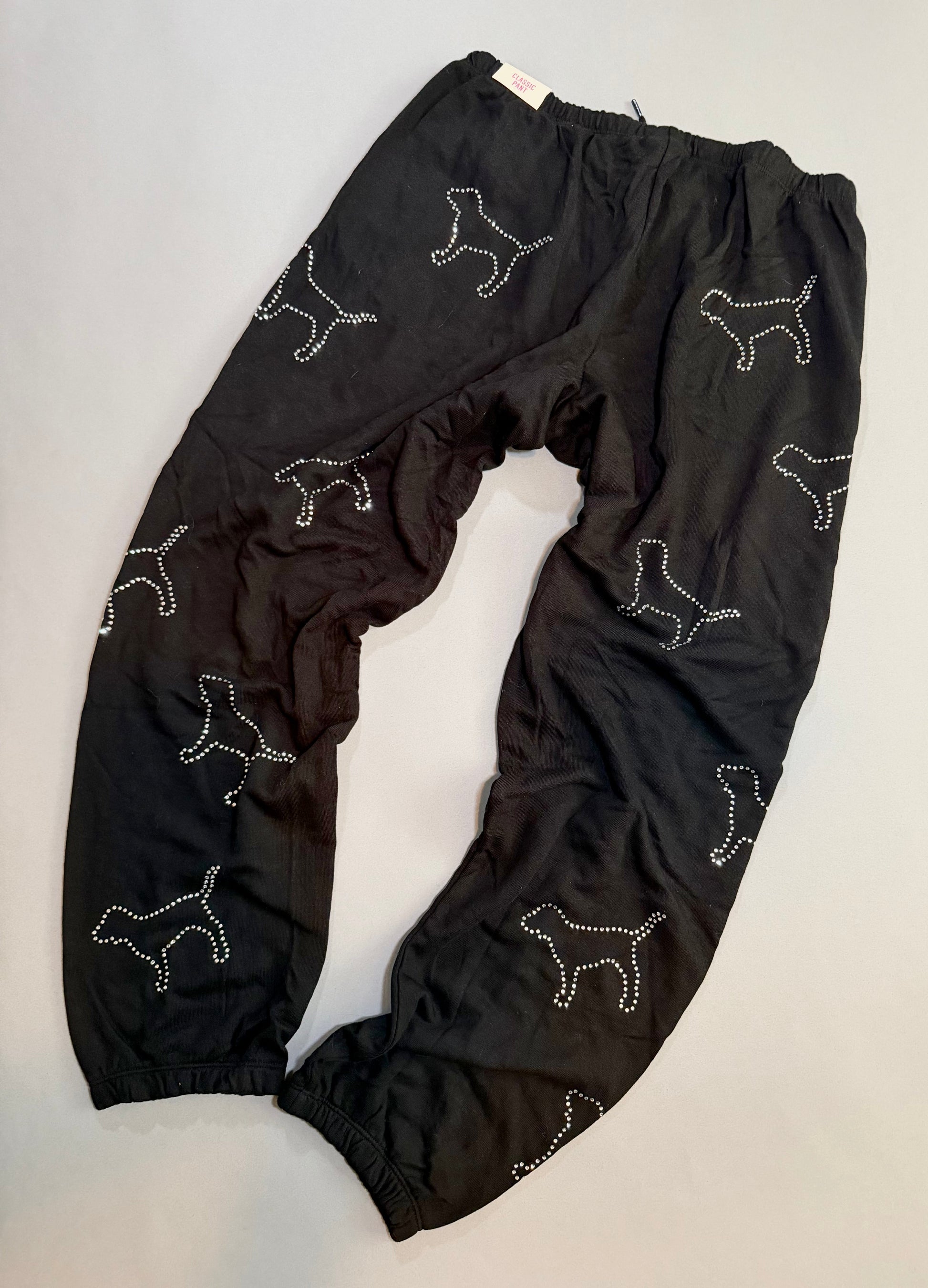 Black PINK sweatpants with scattered rhinestone dog silhouettes.