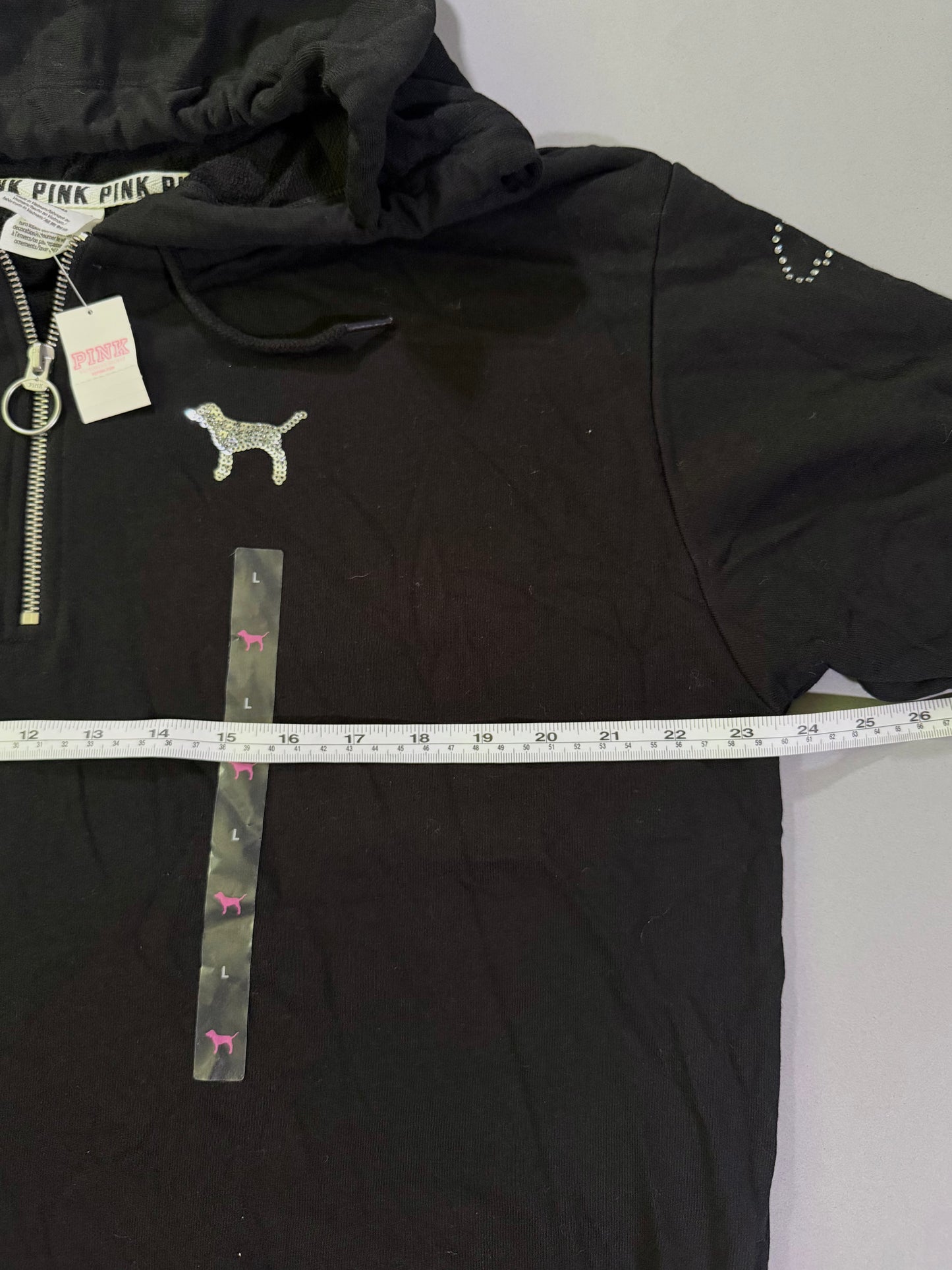 Black vs pink 1/4 zip with sequin dog and measuring tape showing pit to pit measurement 