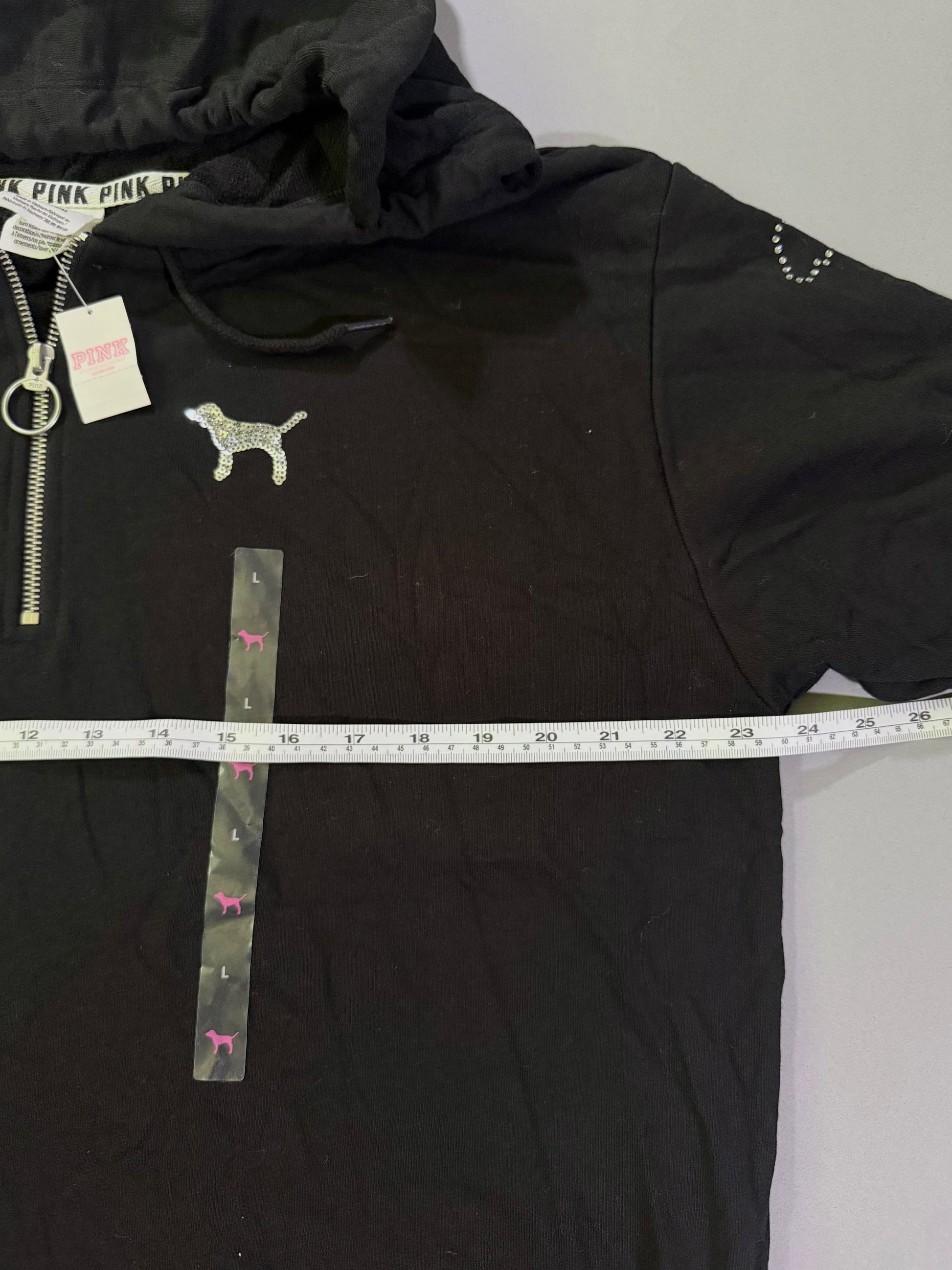 Black vs pink 1/4 zip with sequin dog and measuring tape showing pit to pit measurement 
