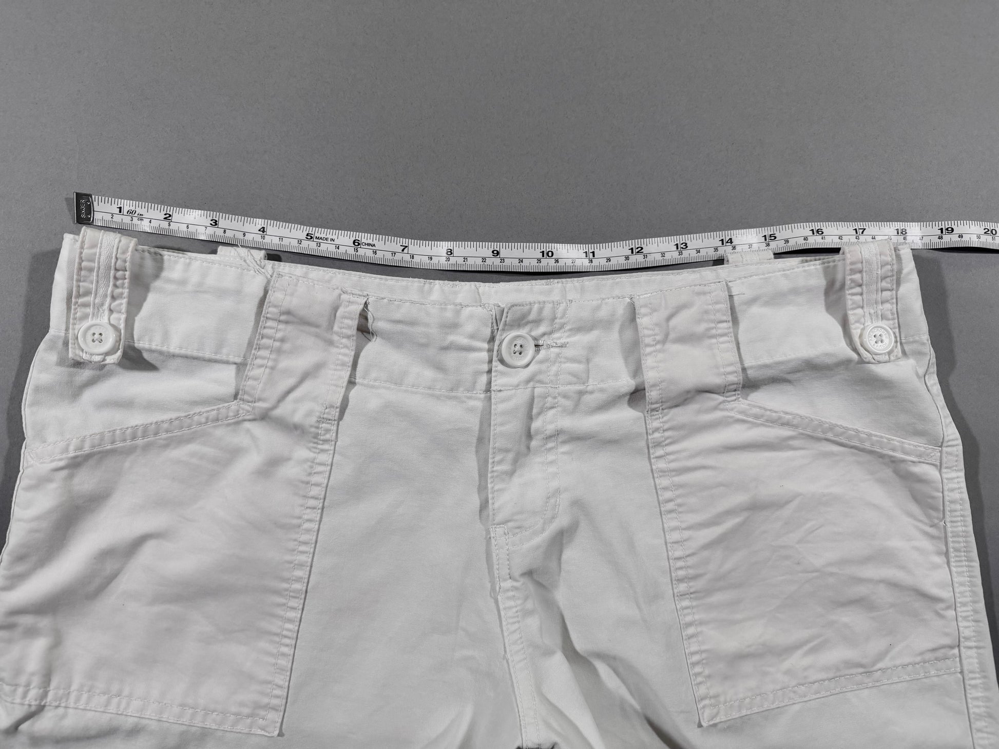 Waistband detail of vintage Y2K Abercrombie & Fitch white cargo pants showing front button closure, oversized front pockets, and waist measurement.