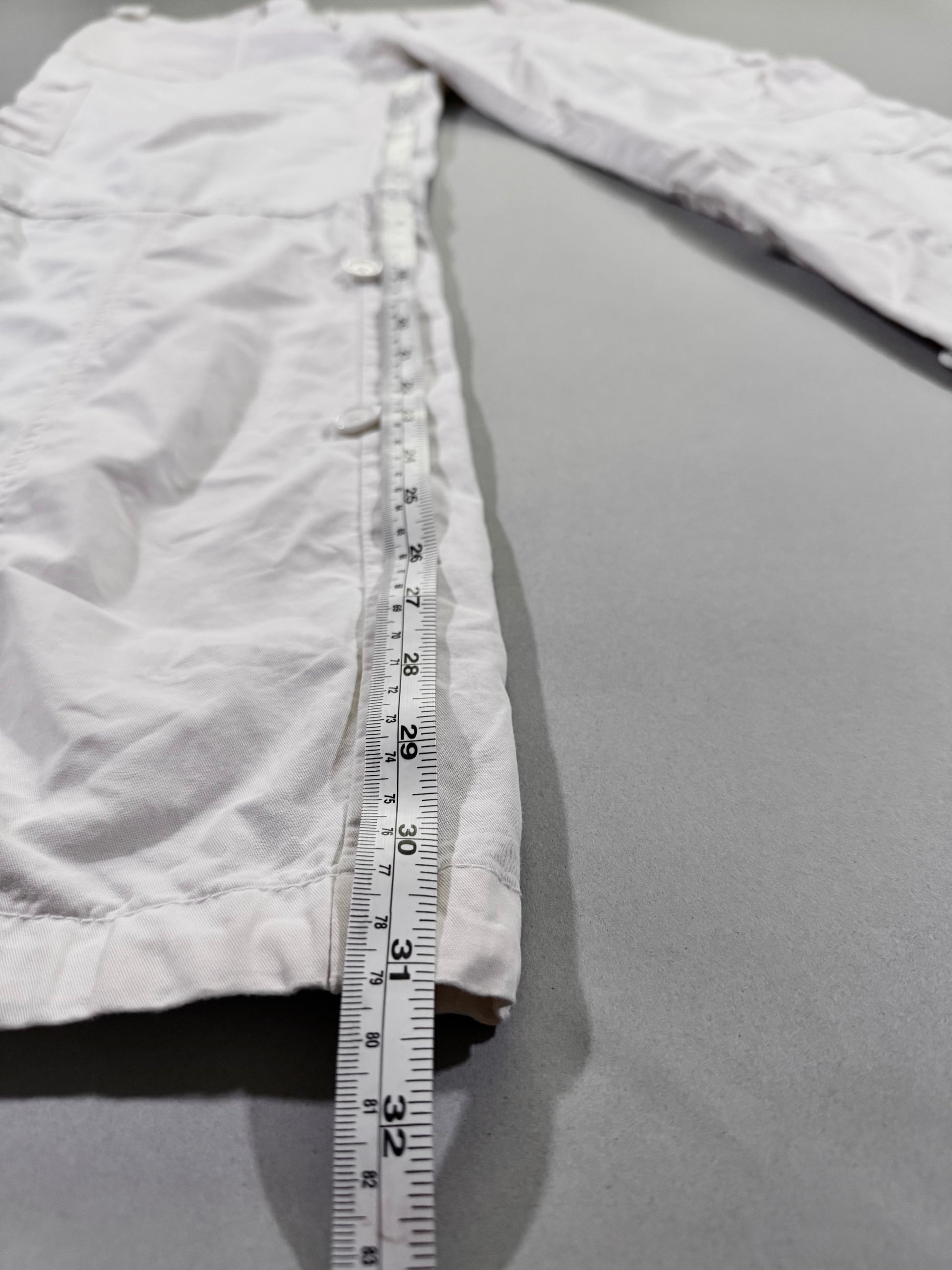 Side view showing inseam measurement and adjustable button-tab detailing along the leg of vintage Abercrombie & Fitch white cargo pants.