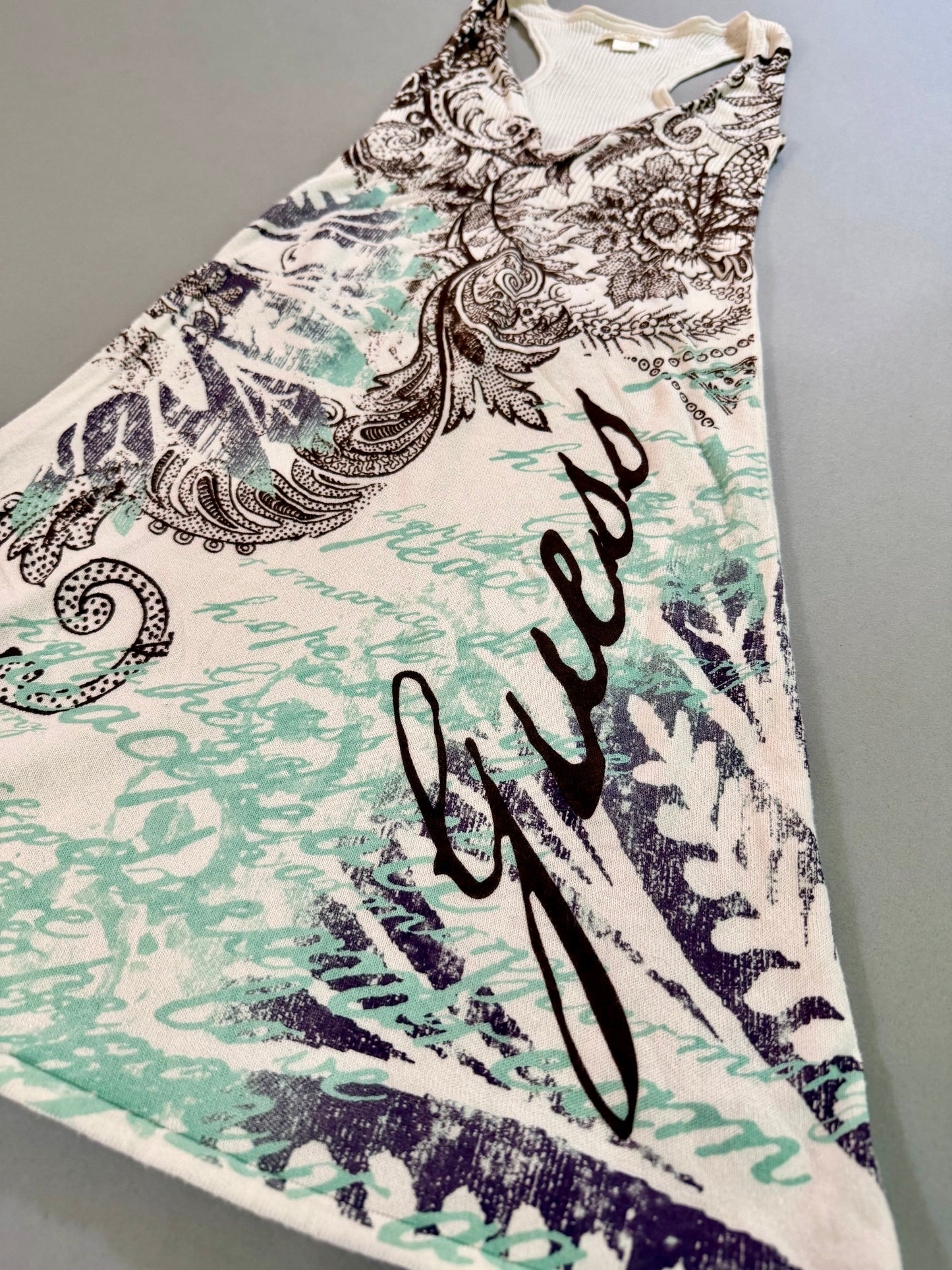 Angled close-up of the Guess logo and layered paisley graphic on the ribbed sleeveless dress.
