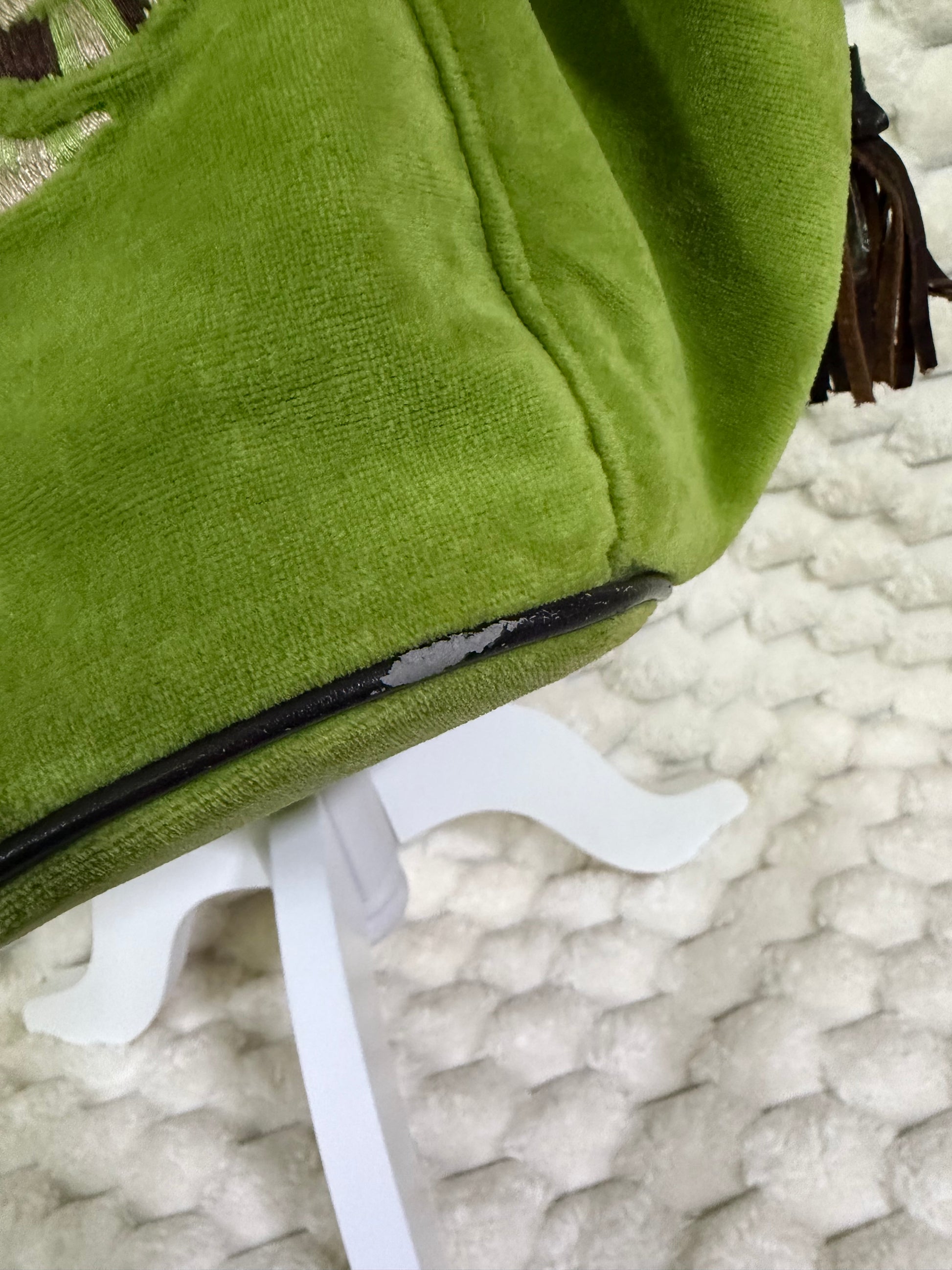 Close-up of vintage Juicy Couture green velour tote showing wear and peeling along the brown bottom piping.