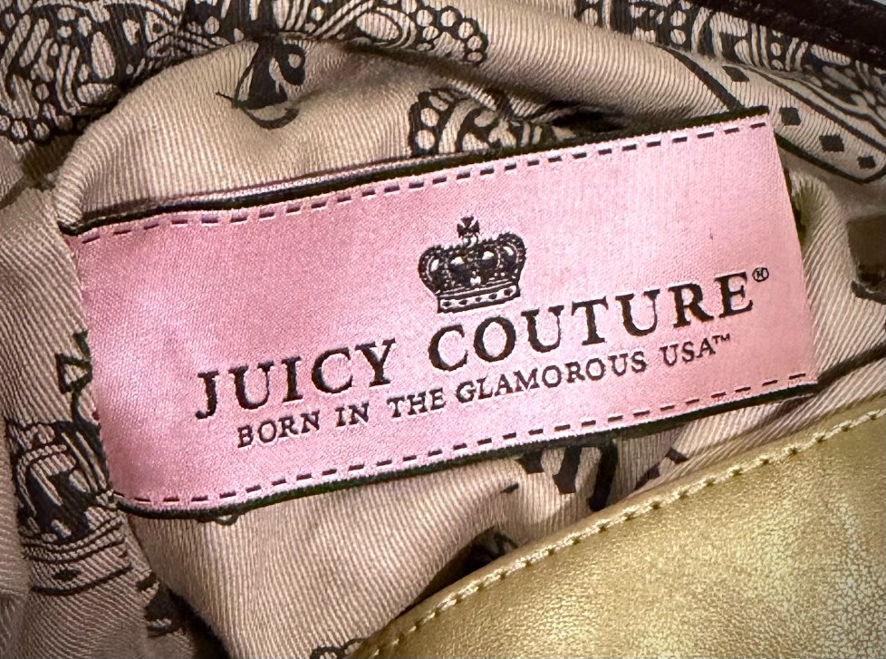 Interior of juicy couture purse showing novelty pockets and vintage pink garment tag from the 2000s.