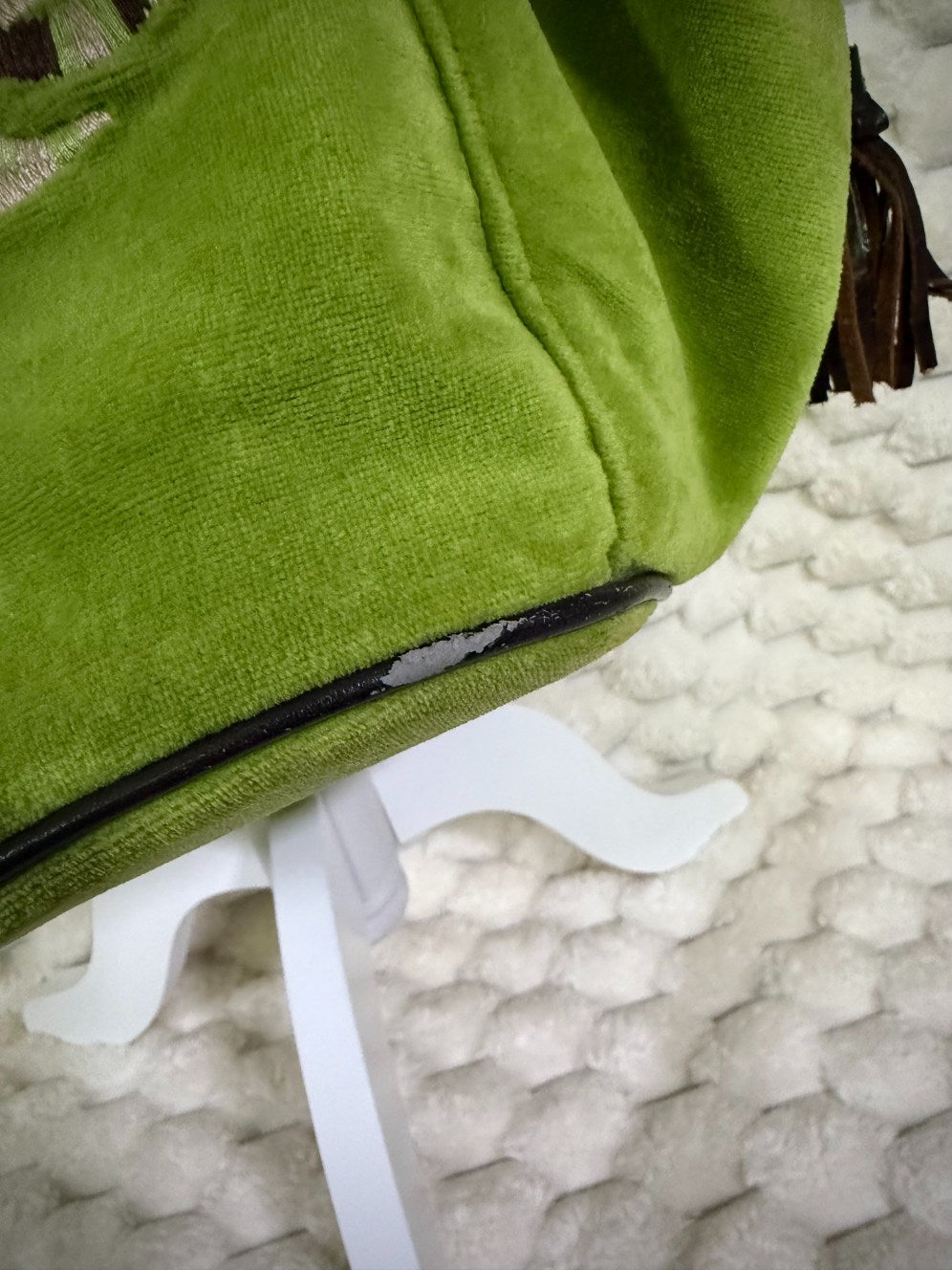 Close-up of vintage Juicy Couture green velour tote showing wear and peeling along the brown bottom piping.