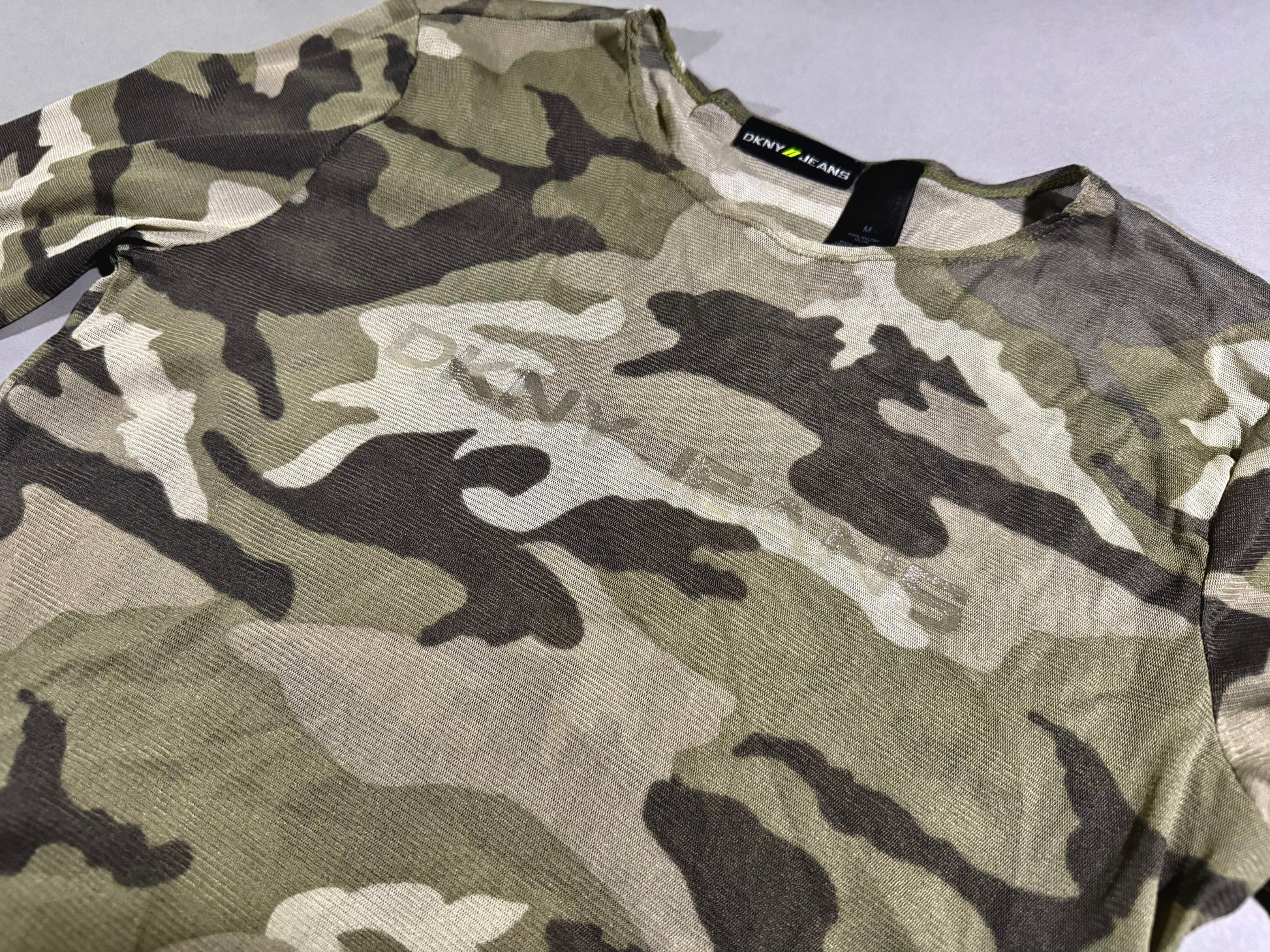 Close-up angled photo of y2k era mesh camo printed long sleeve shirt with subtle DKNY branding