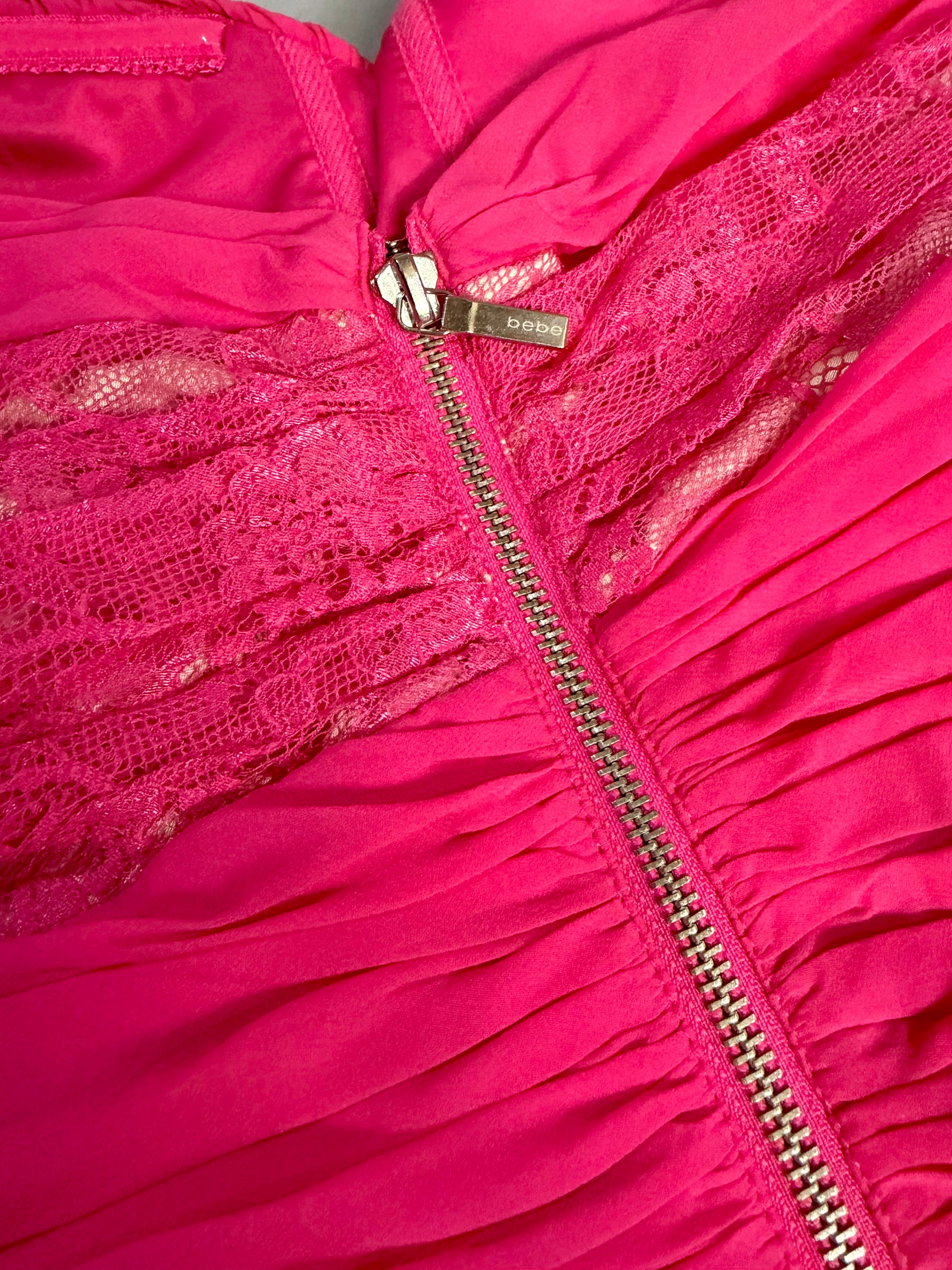 Close-up of the signature bebe logo zipper pull and floral lace detail.
