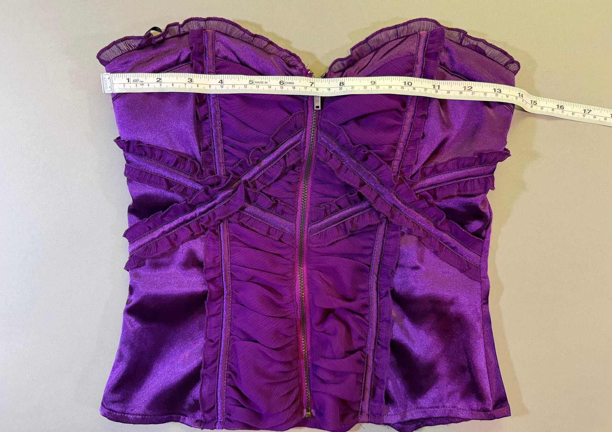 Satin and chiffon Bebe top with measuring tape showing 13.5 inches pit to pit