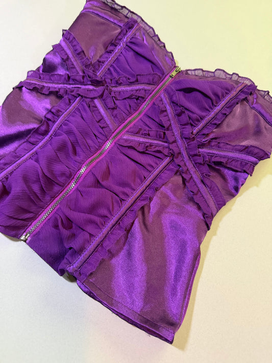 Angled photo of purple satin corset top from Bebe with chiffon ruffles and metal zipper down middle 