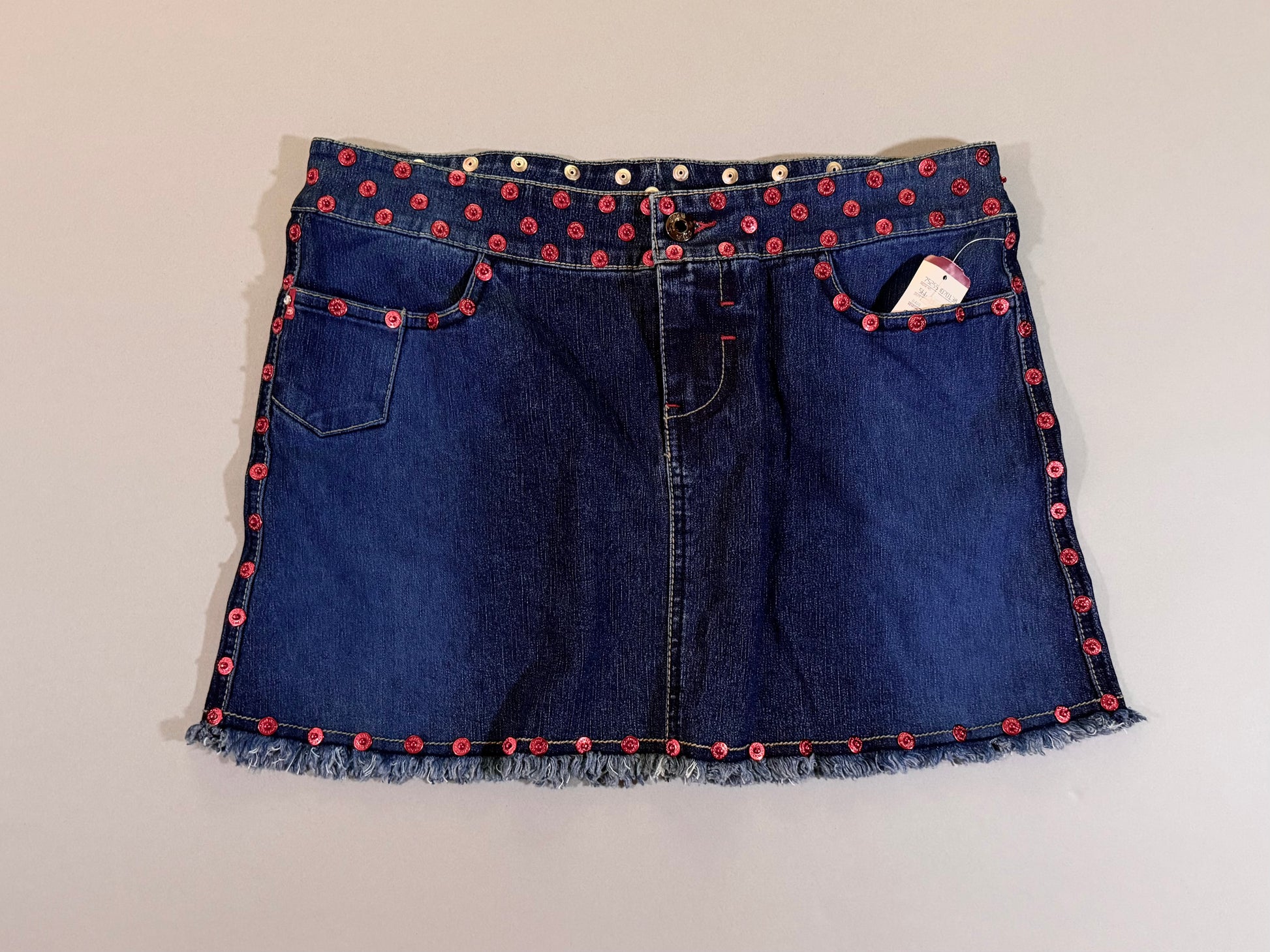 Front view of 2003 Ecko denim skirt with red rivets studding top, bottom, and side borders 