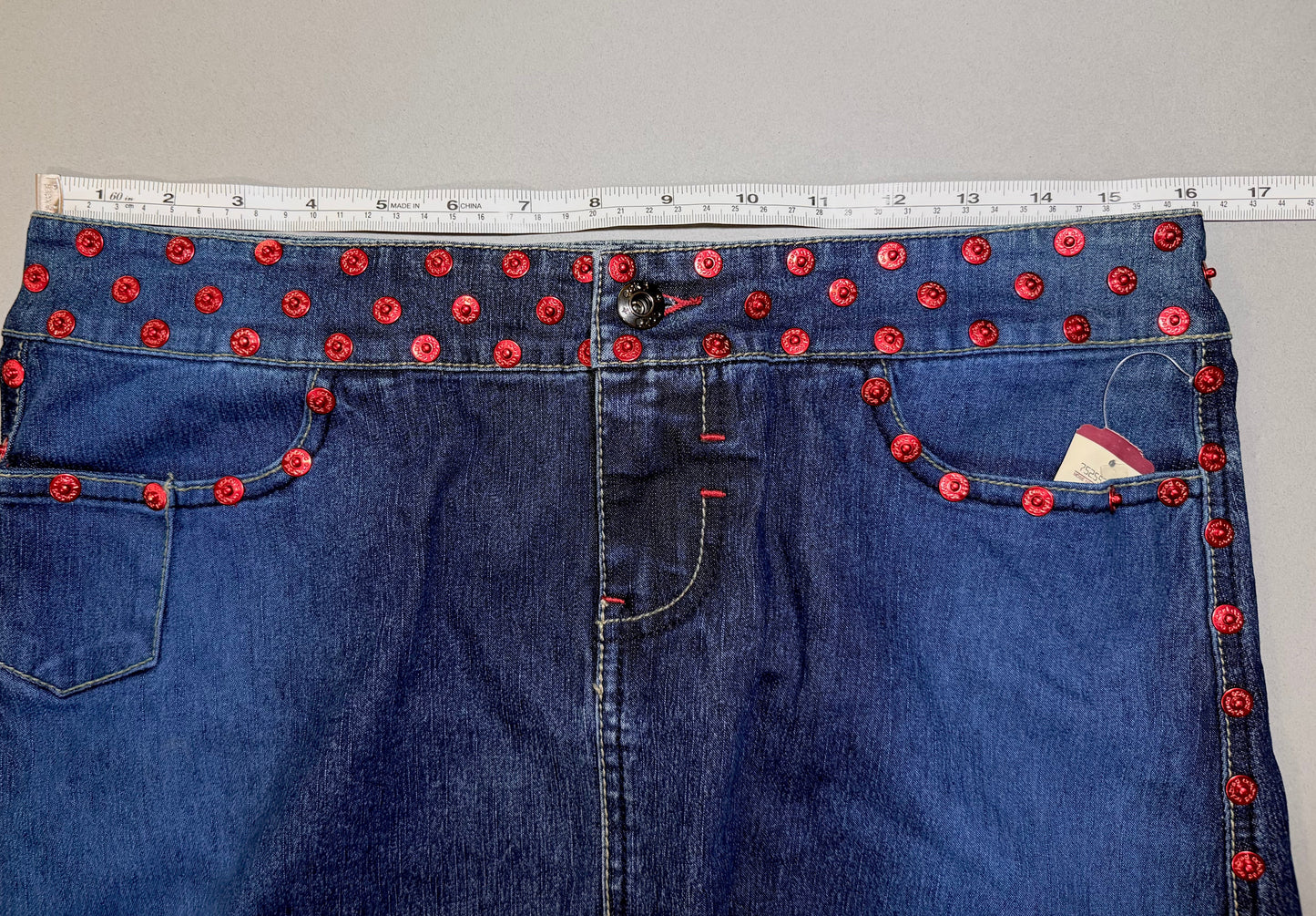 Close up of Ecko denim mini skirt with measuring tape showing 16 inches (doubled makes 32 inches waist measurement) 