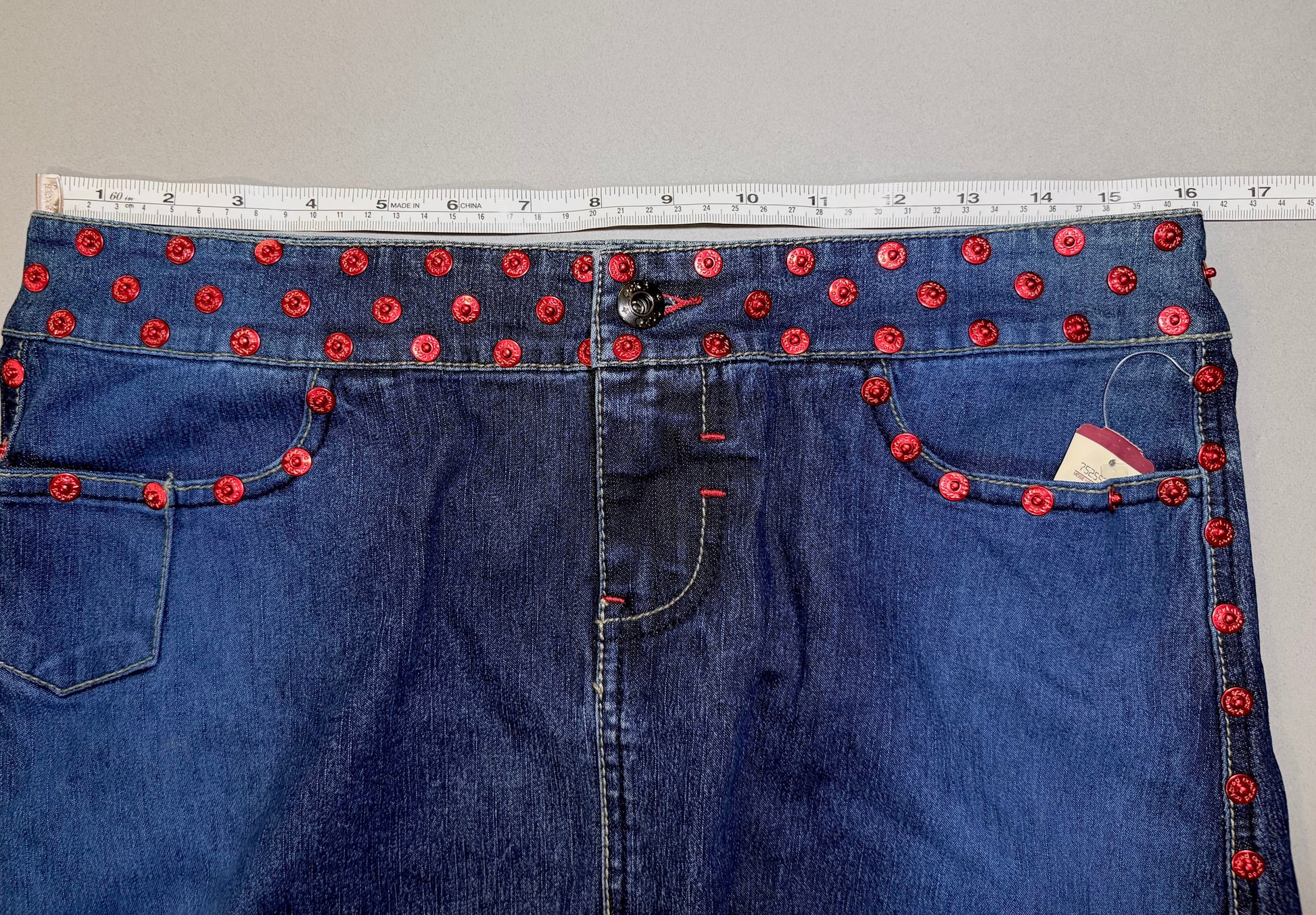 Close up of Ecko denim mini skirt with measuring tape showing 16 inches (doubled makes 32 inches waist measurement) 