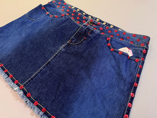 Angled photo of y2k Ecko denim mini skirt with red rivets studding accents