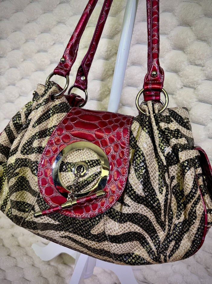 Close-up of zebra print handbag with decorative toggle and croc embossed front flap