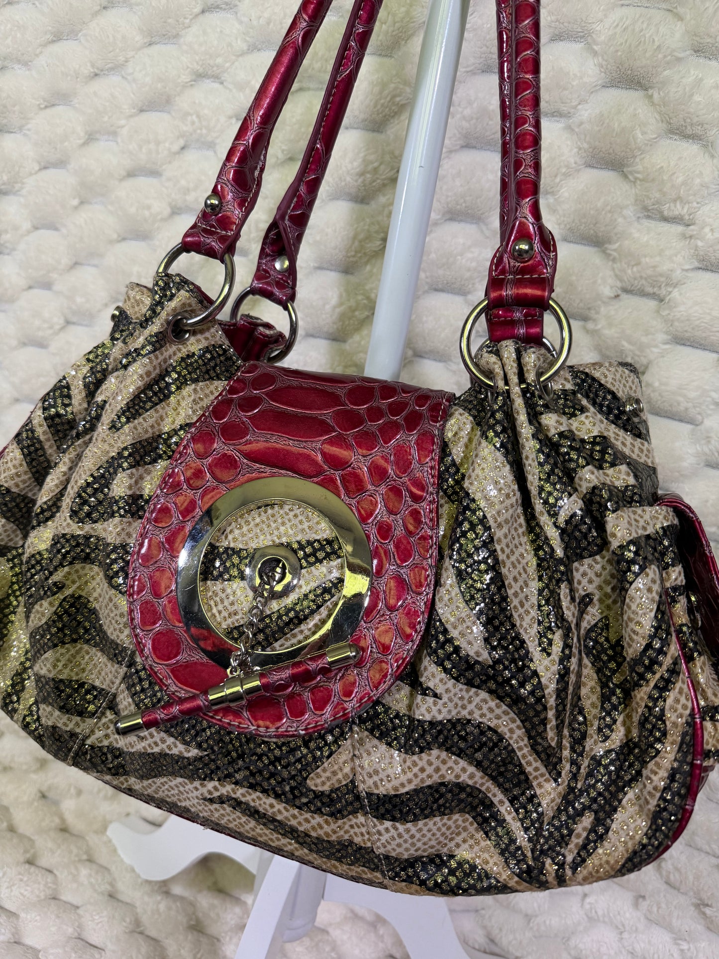 Close-up of zebra print handbag with decorative toggle and croc embossed front flap