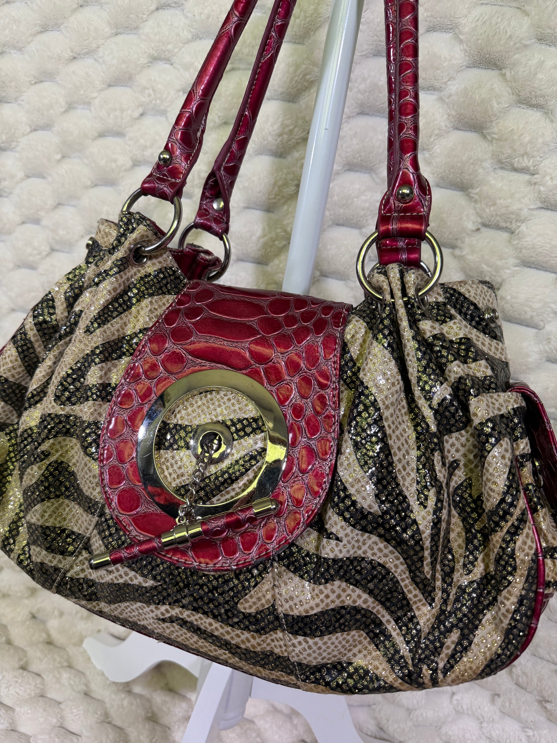 Close-up of zebra print handbag with decorative toggle and croc embossed front flap