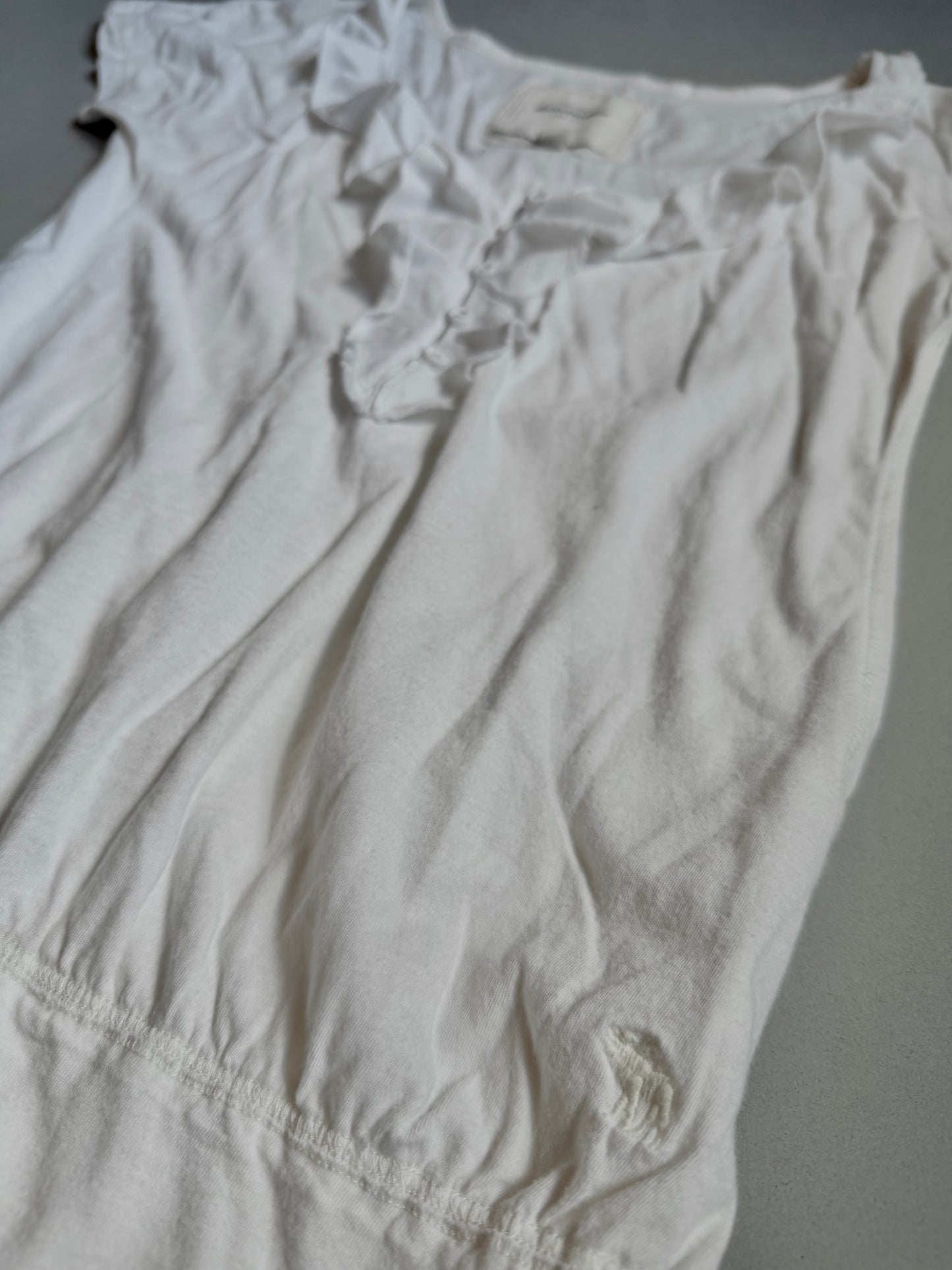 White Abercrombie & Fitch ruffle top from bottom angle showing embroidered moose logo. 