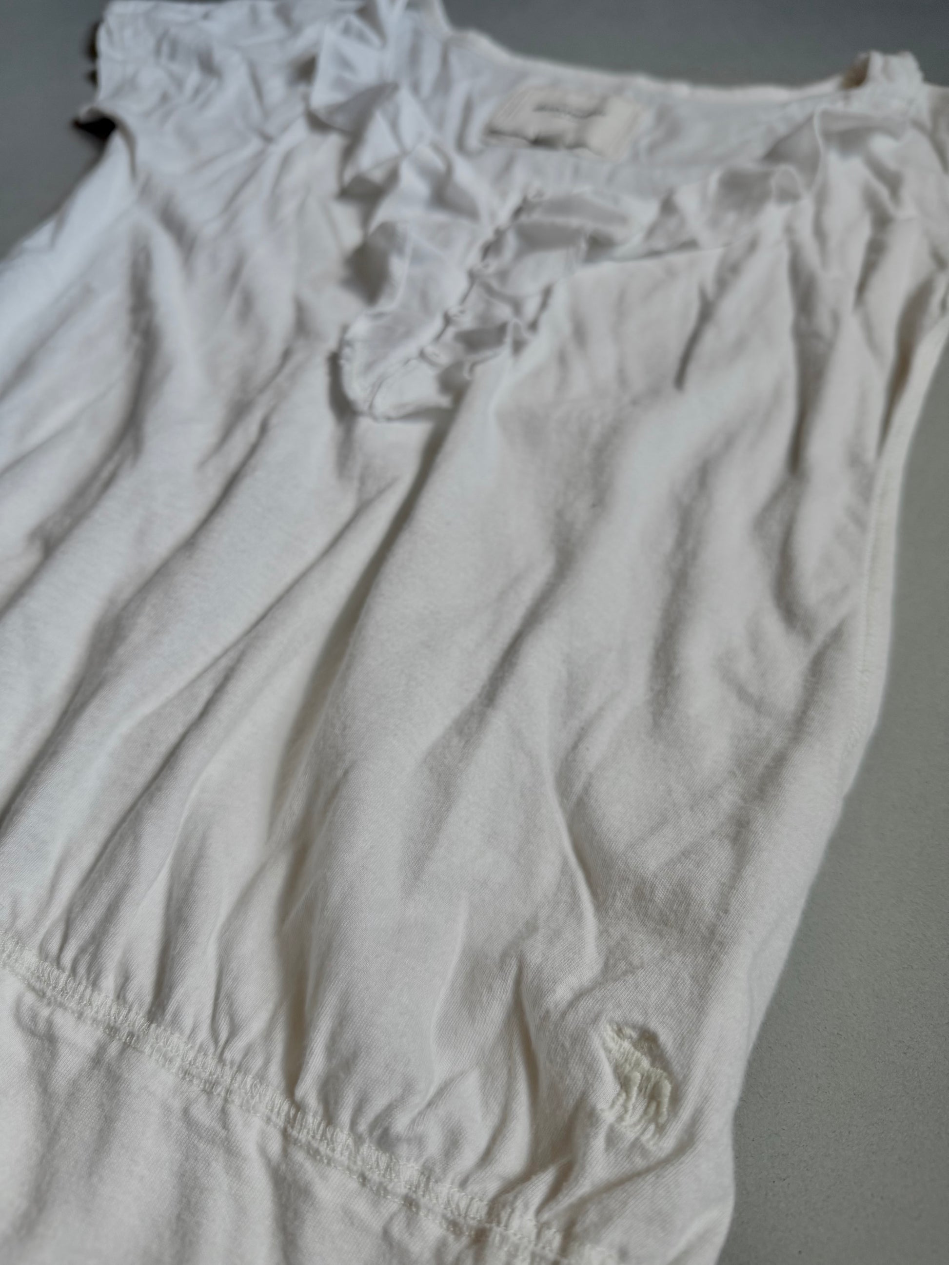 White Abercrombie & Fitch ruffle top from bottom angle showing embroidered moose logo. 