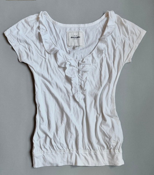 White Abercrombie & Fitch ruffle top with bubble silhouette against grey backdrop 