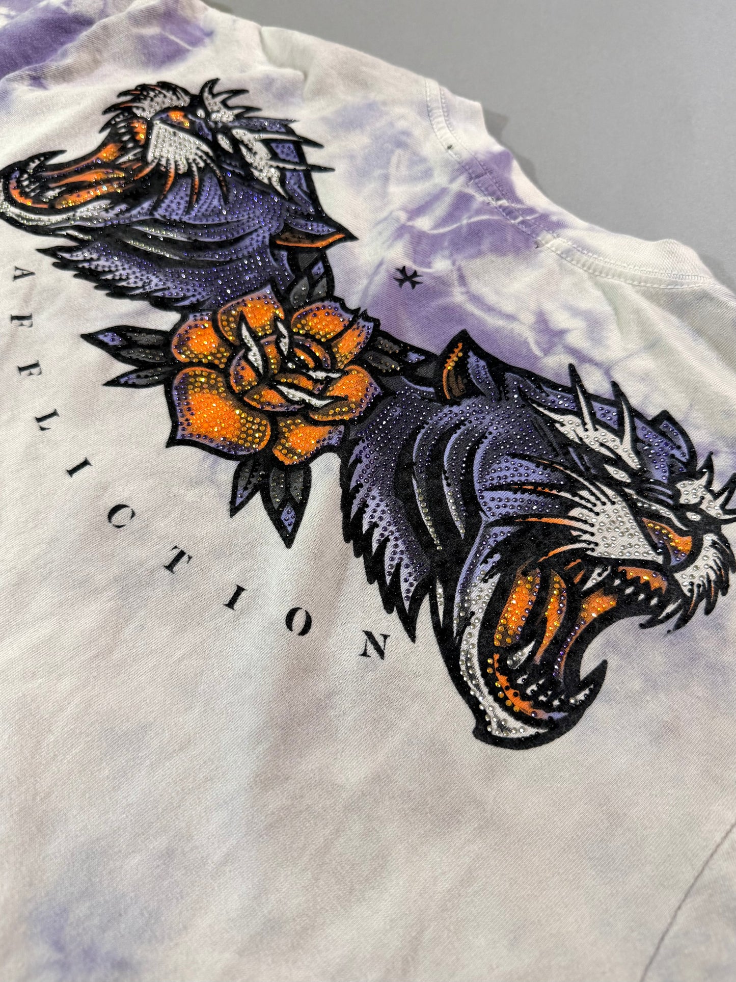 Close-up of the rhinestone tiger heads, orange rose and Affliction lettering on the back graphic.