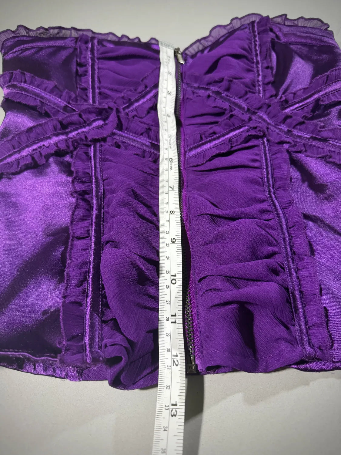 Purple satin and chiffon Bebe top with measuring tape showing 12 inches length