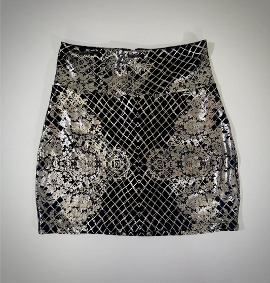 Bebe metallic silver foil mini skirt in black with lace-inspired geometric pattern, front view.