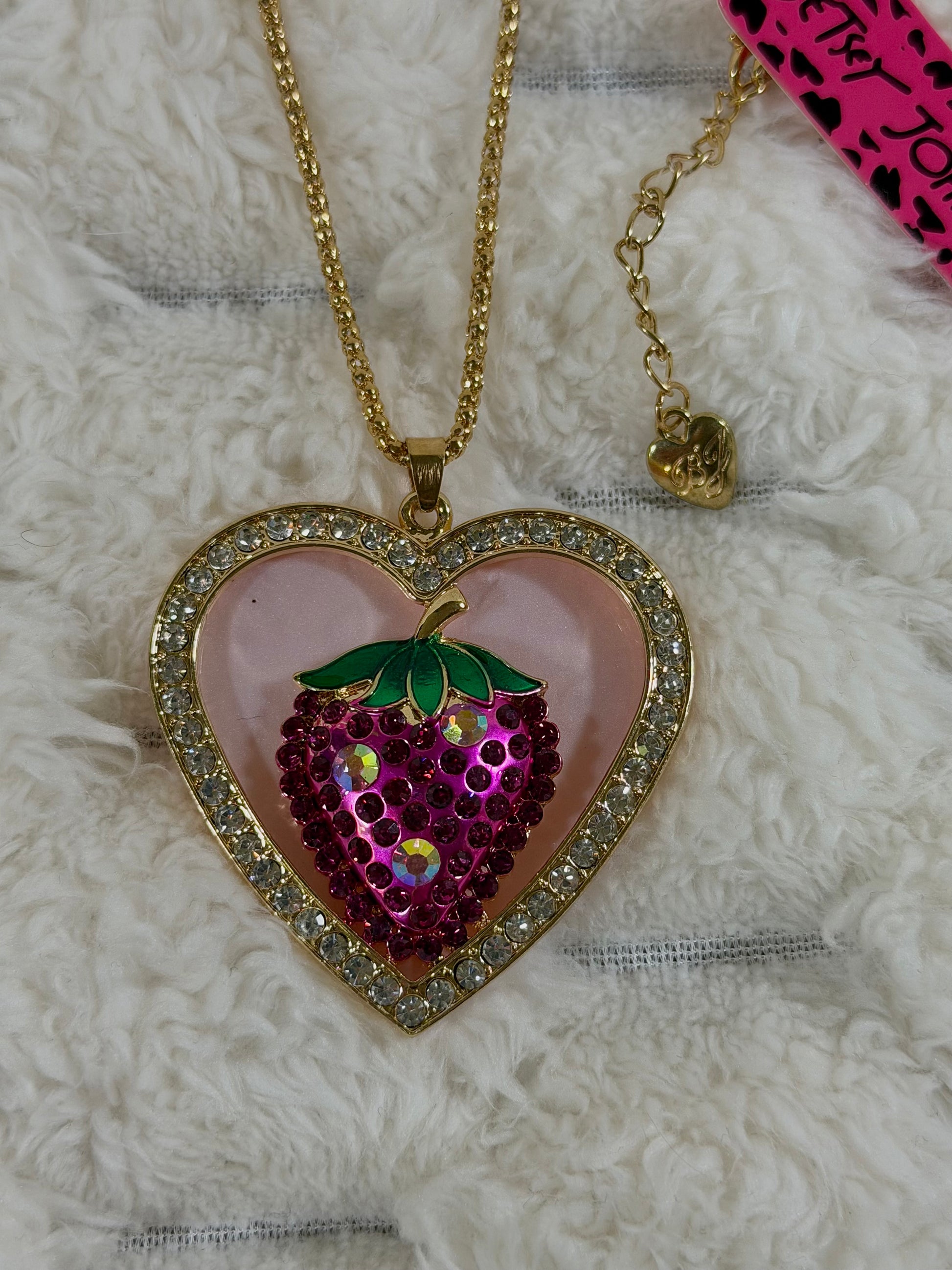 Close-up of the Betsey Johnson heart pendant with clear rhinestones, pink crystal strawberry, green enamel leaves, and gold-tone chain.