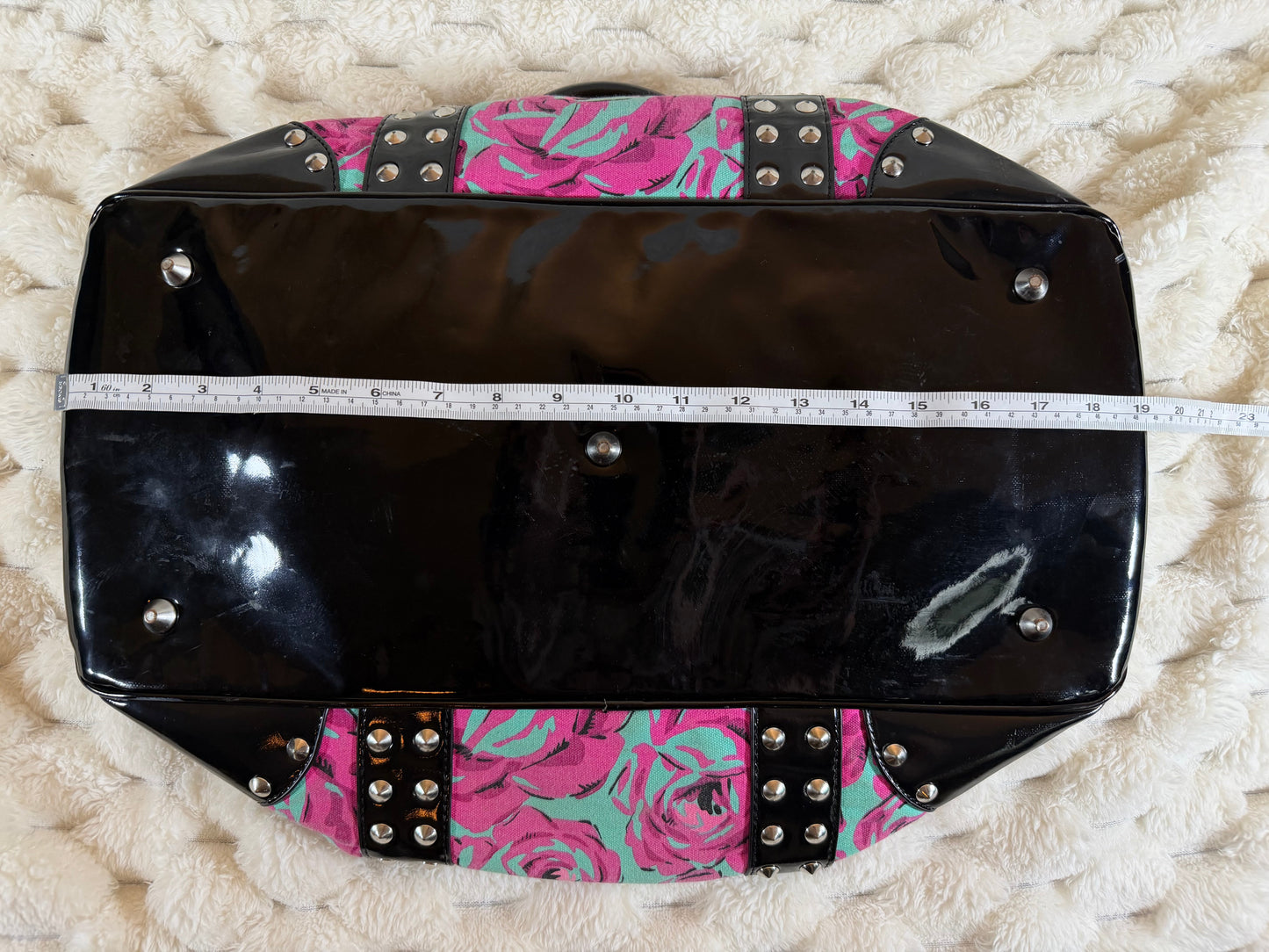 Length measurement of the Betseyville floral satchel shown with measuring tape against the patent leather base, approximately 19 inches.