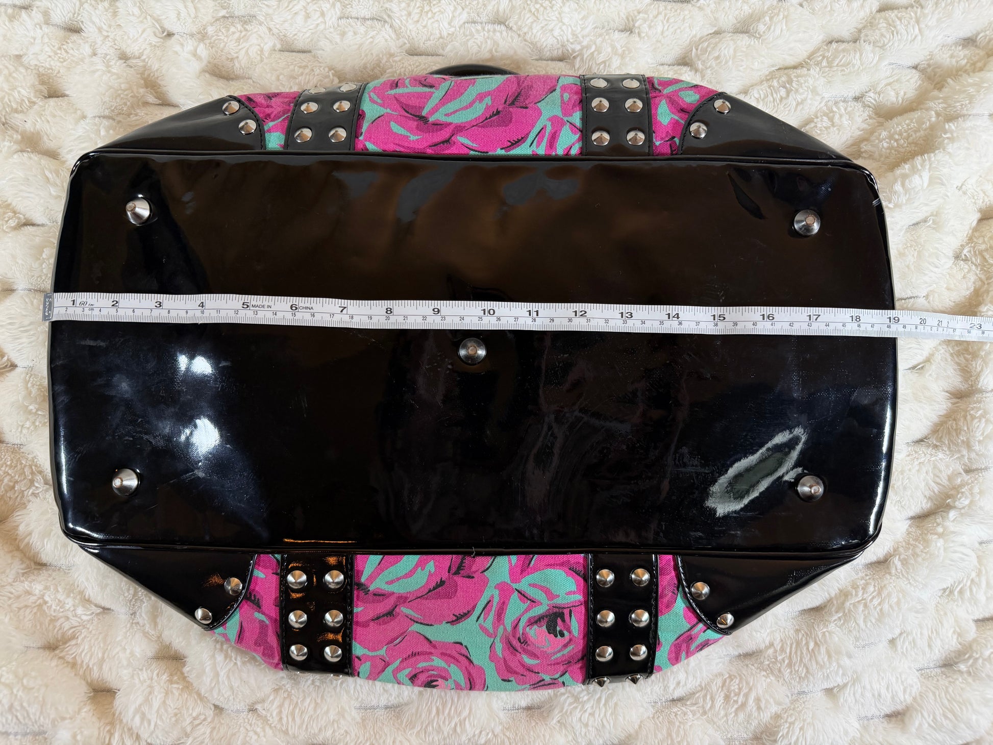 Length measurement of the Betseyville floral satchel shown with measuring tape against the patent leather base, approximately 19 inches.