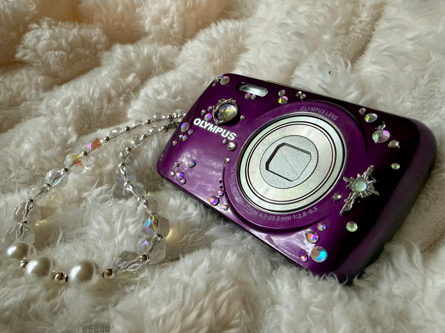 Purple Olympus digital camera decorated with rhinestones and celestial charms 
