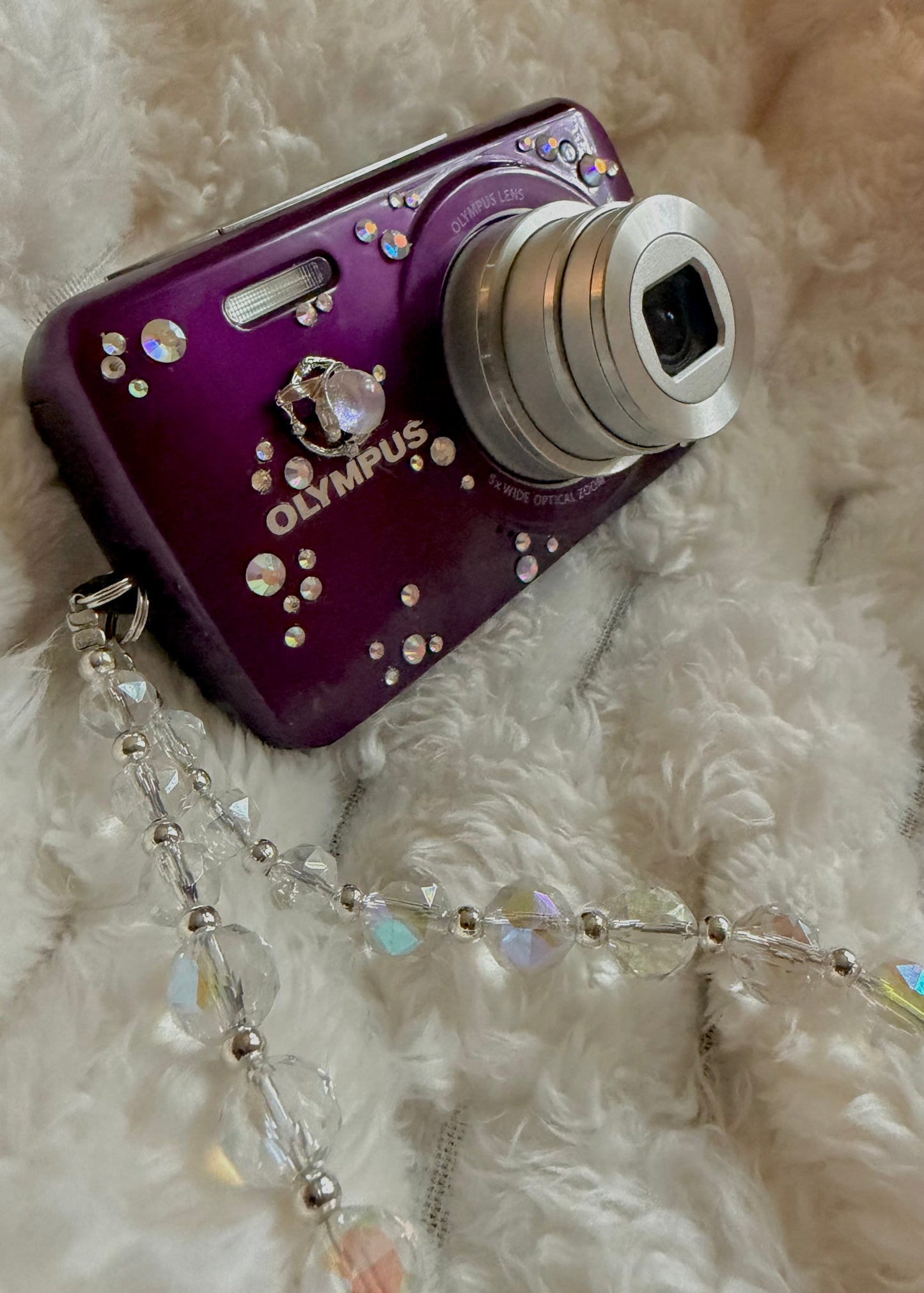 Close up of purple Olympus digital camera showing celestial moon fairy charms and aurora borealis rhinestones 