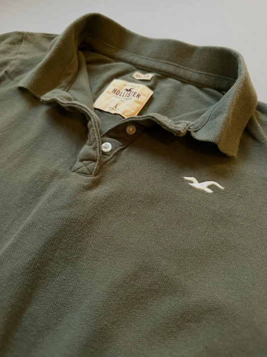 Close up of olive green Hollister polo collar and embroidered branding 