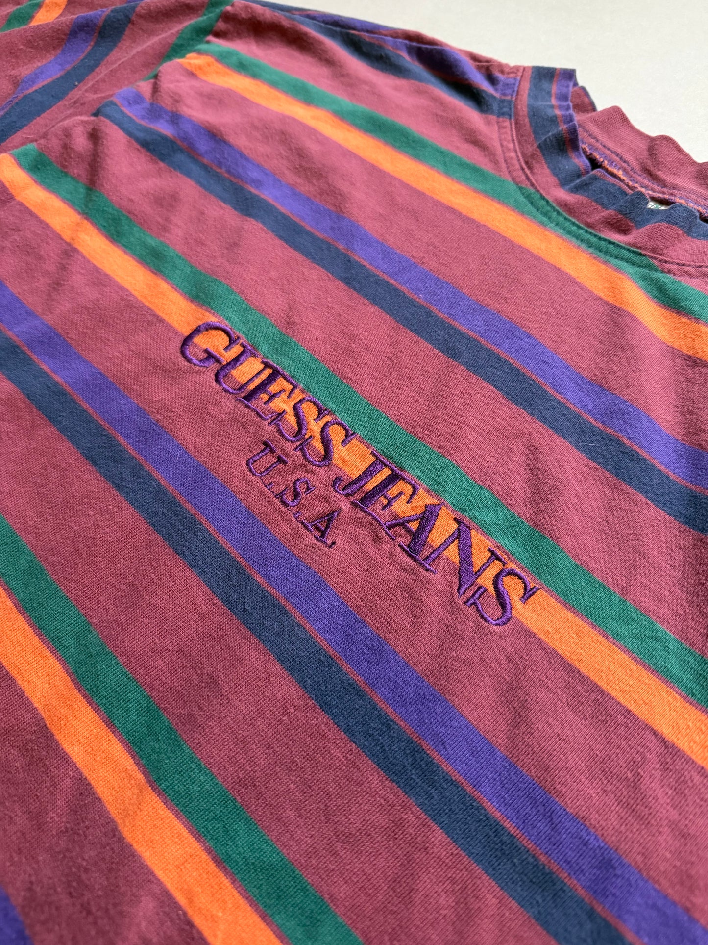 Close-up of embroidered “Guess Jeans U.S.A.” branding vintage 90s striped Guess t-shirt. 