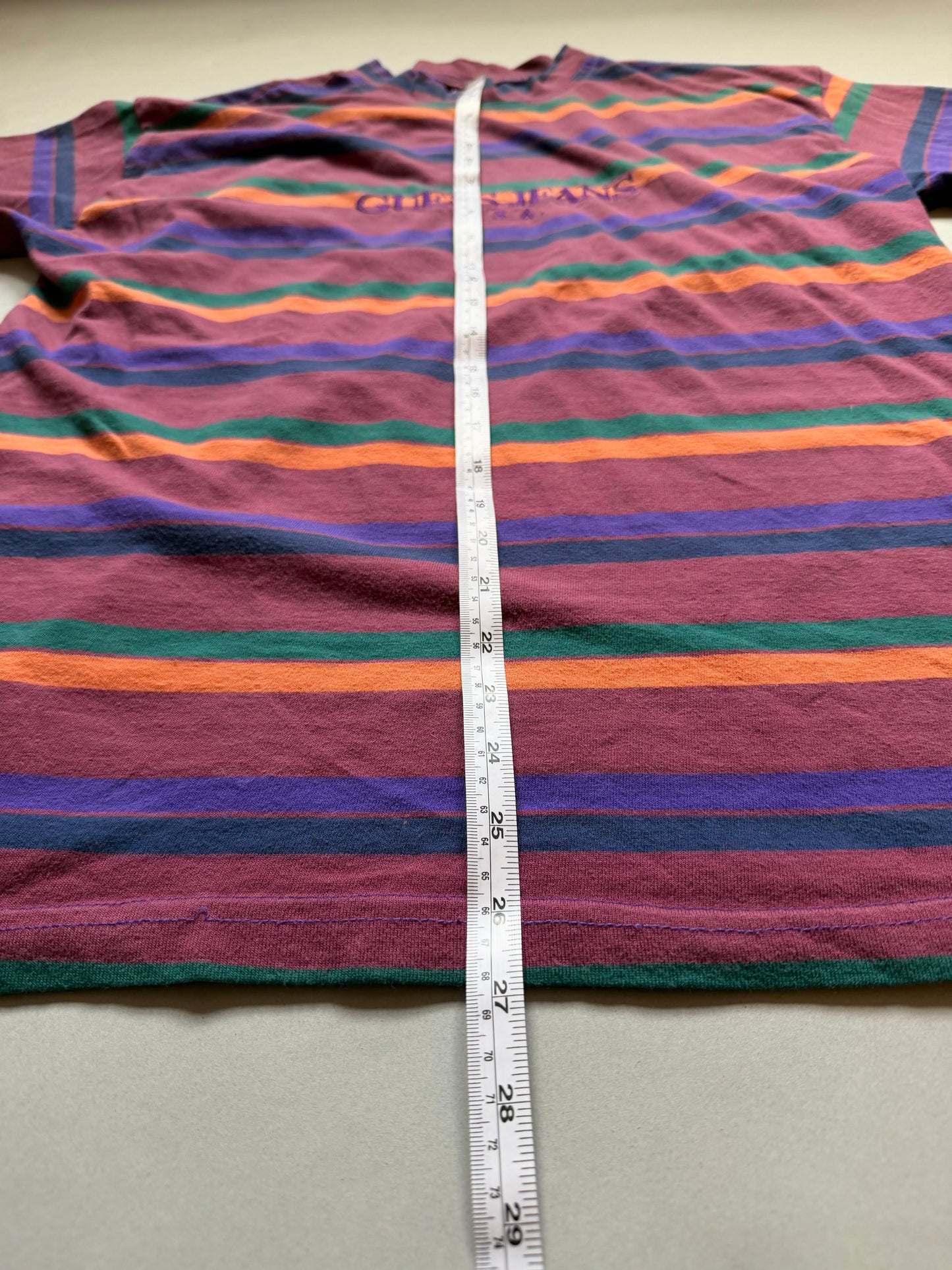 Vintage 90s striped Guess t-shirt with measuring tape showing 27 inches in length. 