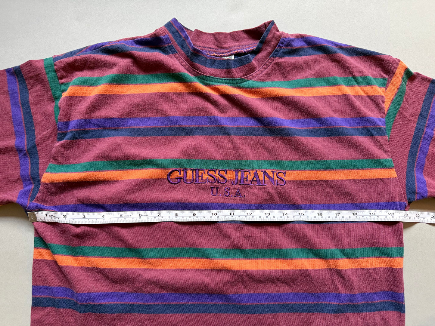 Vintage 90s striped guess tee with measuring tape showing 21 inches pit to pit. 