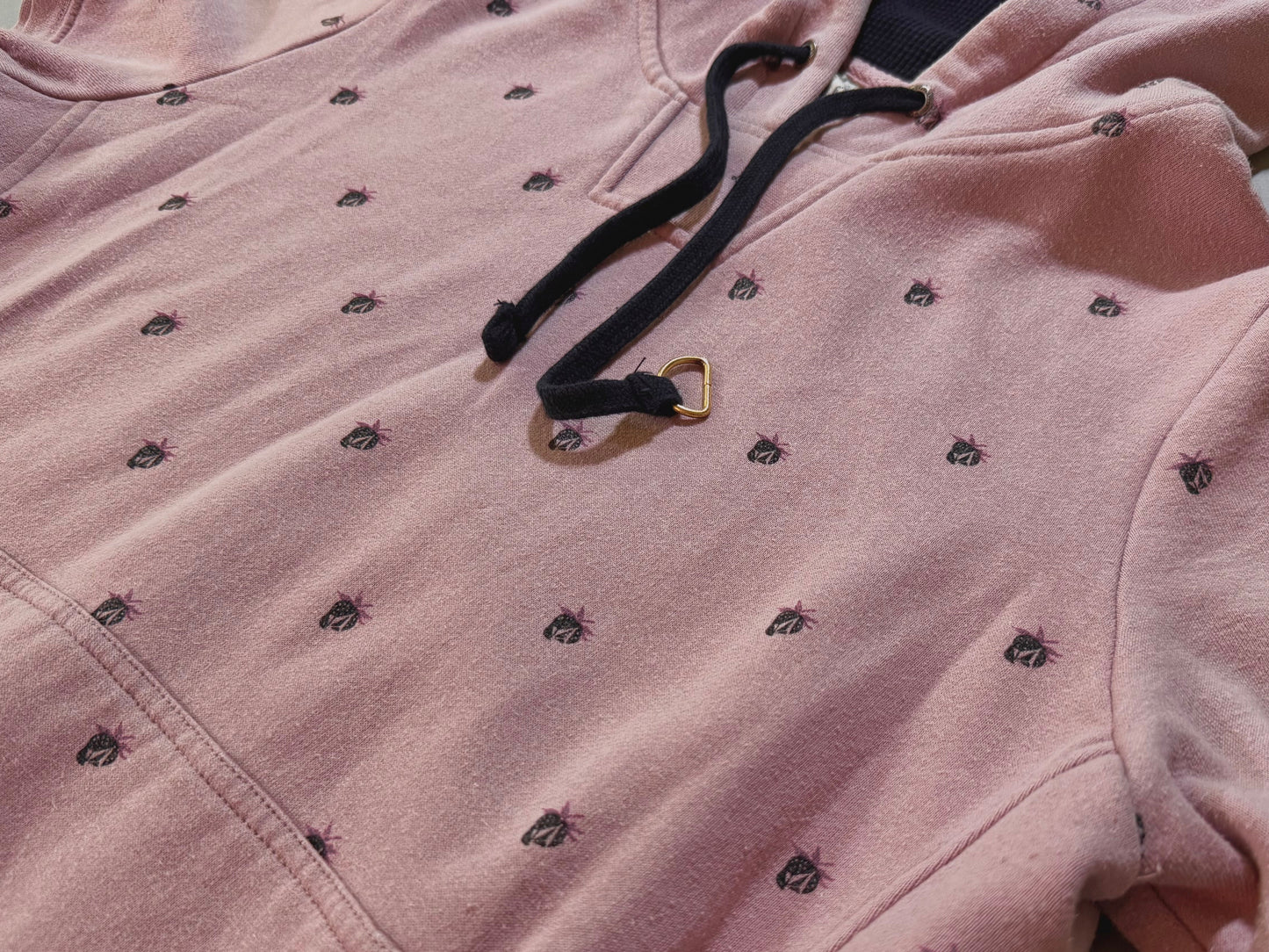 Close-up of vintage Volcom hoodie showing print r Stone/berry pattern, oversized black drawstrings, and soft pink fabric.
