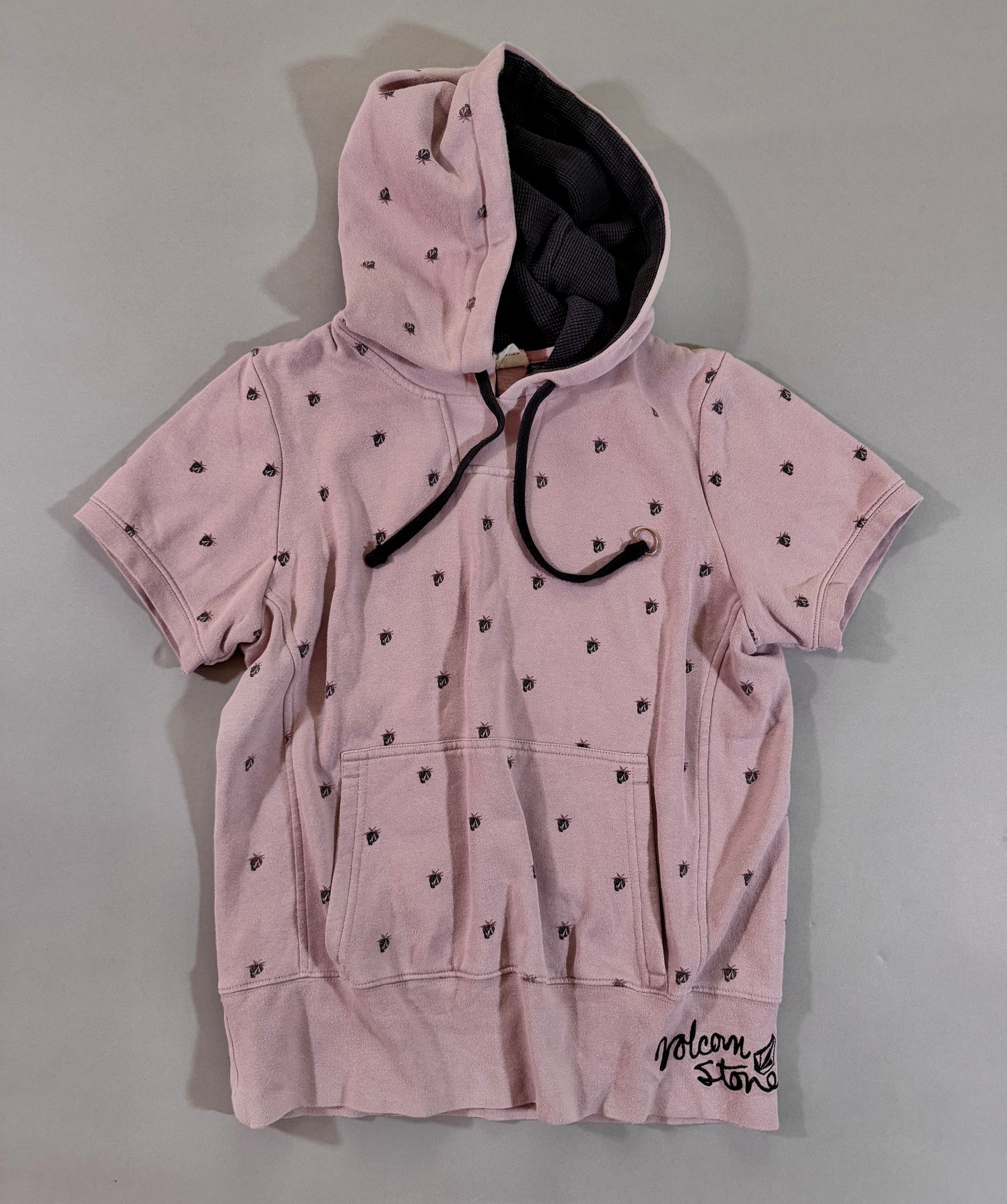 Vintage pink Volcom short sleeve hoodie with all-over berry Stone logo print, kangaroo pocket, and black waffle-lined hood.