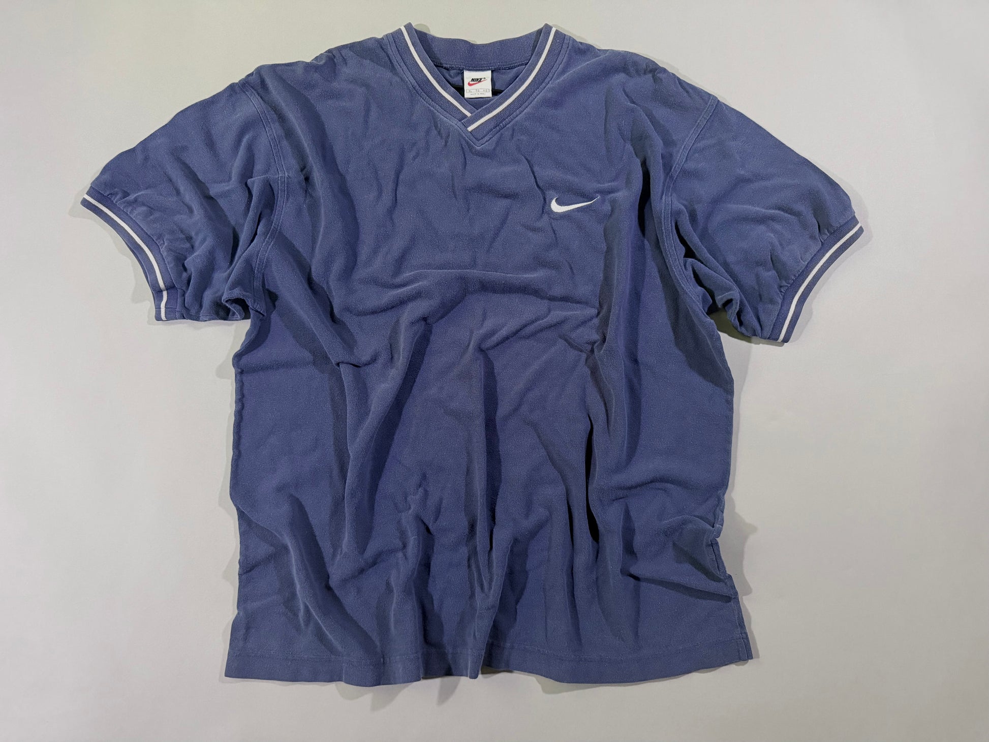 Vintage Nike navy blue V-neck T-shirt with embroidered white Swoosh logo laid flat.