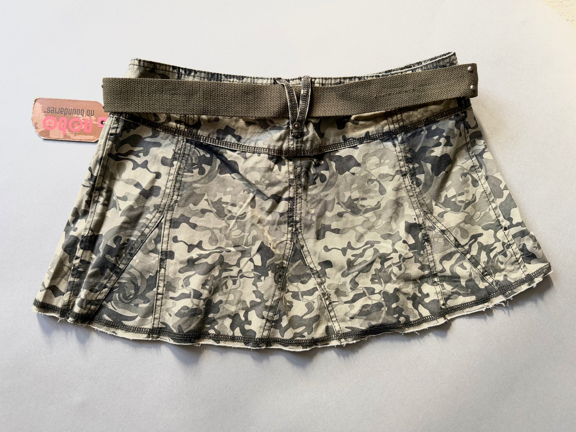 Photo of backside of y2k camo mini skirt with original tags still attached 
