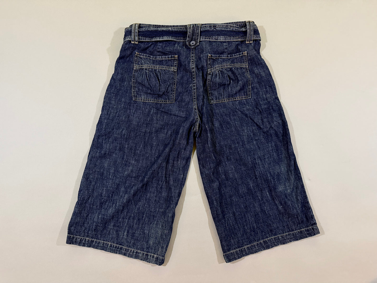 Back view of vintage dark wash cropped longline pants featuring gathered rear patch pockets.