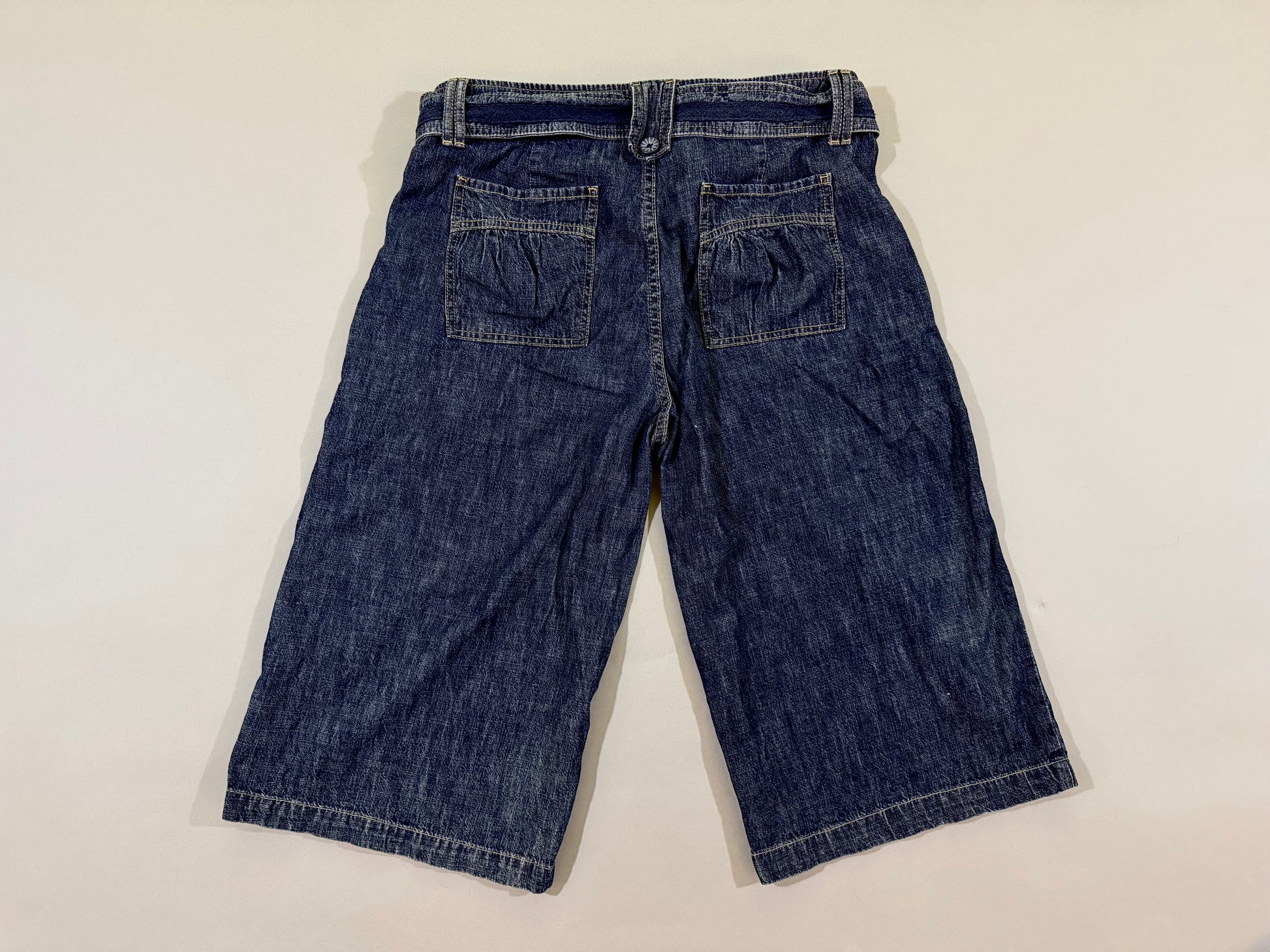 Back view of vintage dark wash cropped longline pants featuring gathered rear patch pockets.
