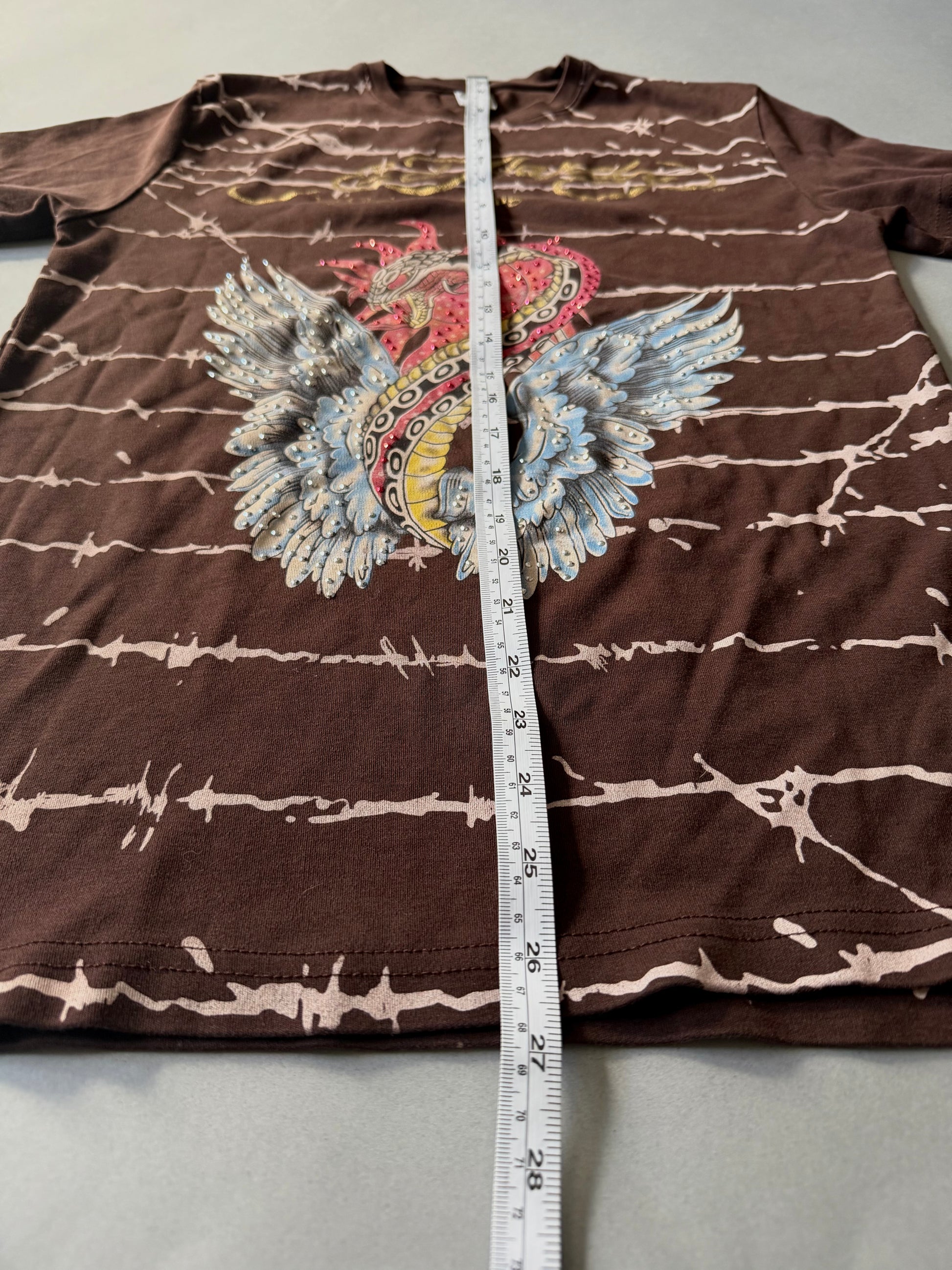 Photo of brown Ed hardy t-shirt with all over barbed wire print and winged snake graphic with rhinestones throughout. Measuring tape showing 26.5 inches length