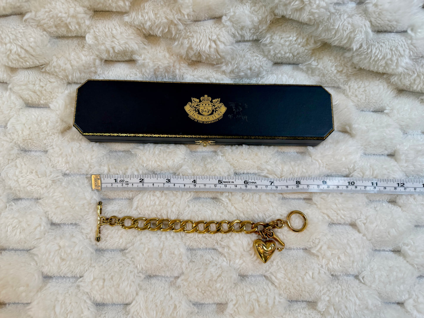 Juicy Couture charm bracelet with original presentation box shown alongside a measuring tape for size reference.
